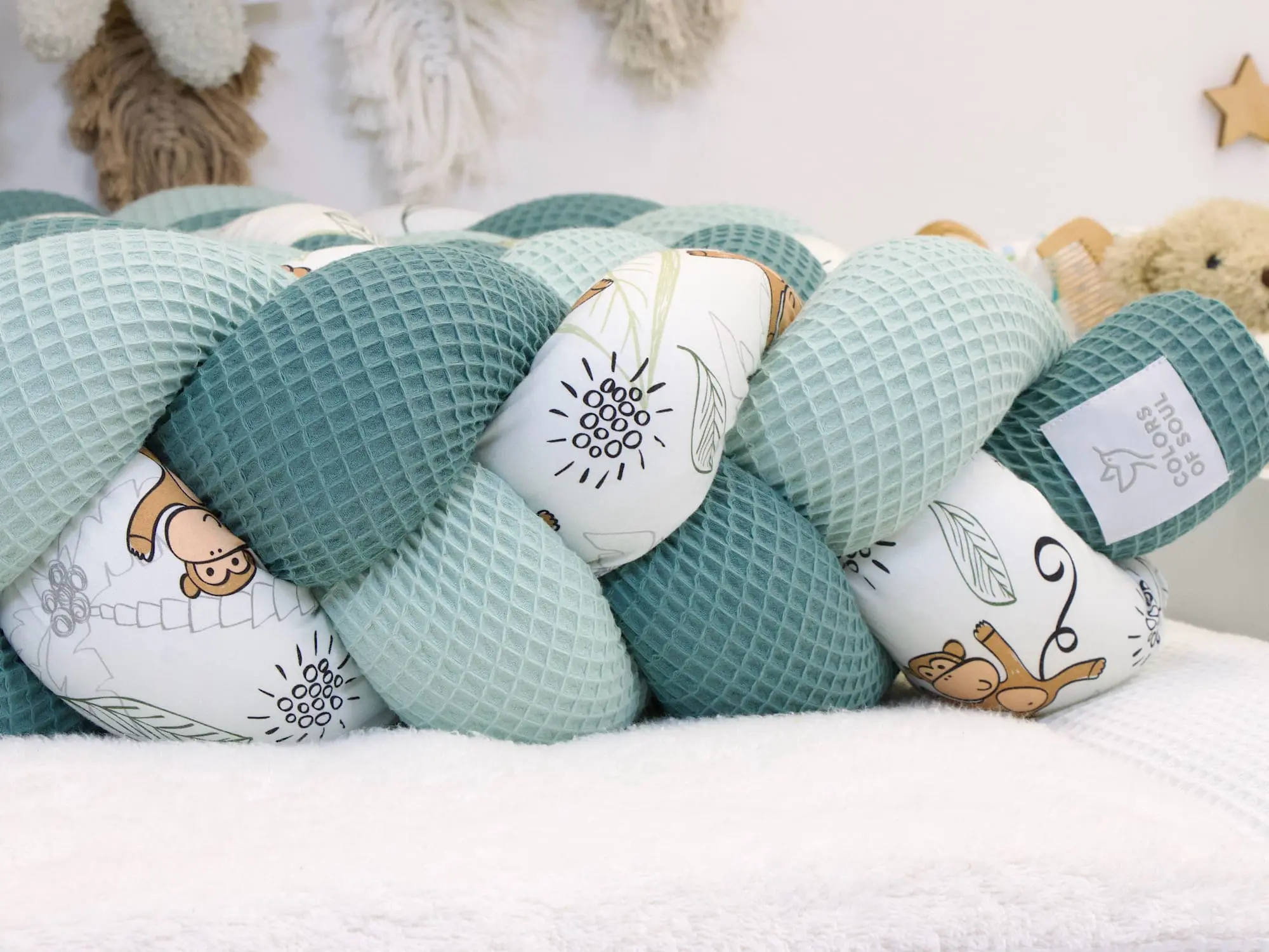 Geflochtene Bettschlange mit Affen-Muster und passenden Kissen im Babybett