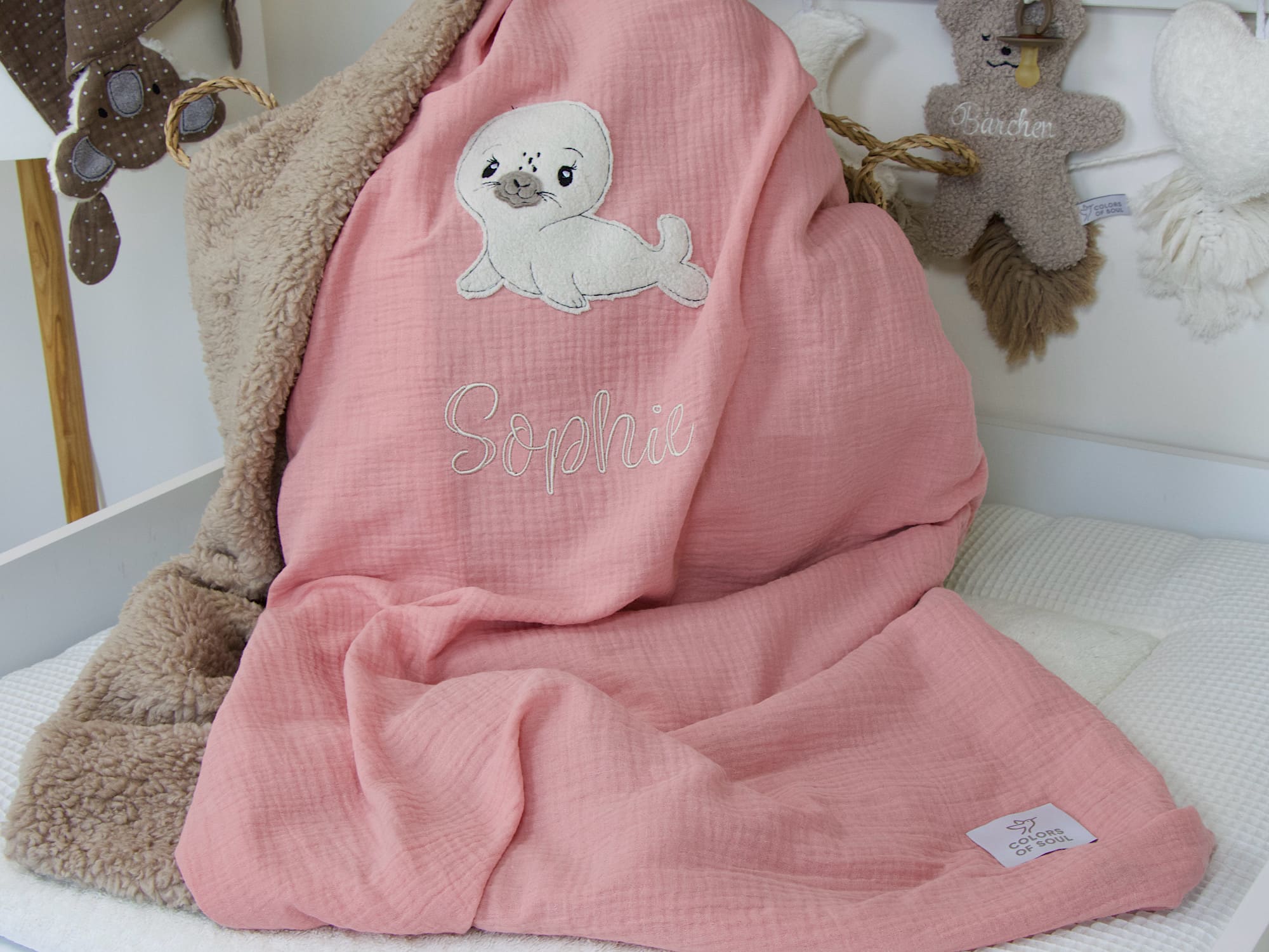Personalisierte Babydecke in Lachsrosa mit Seehund-Applikation und sandfarbenem Teddyplüsch, bestickt mit dem Namen "Sophie".