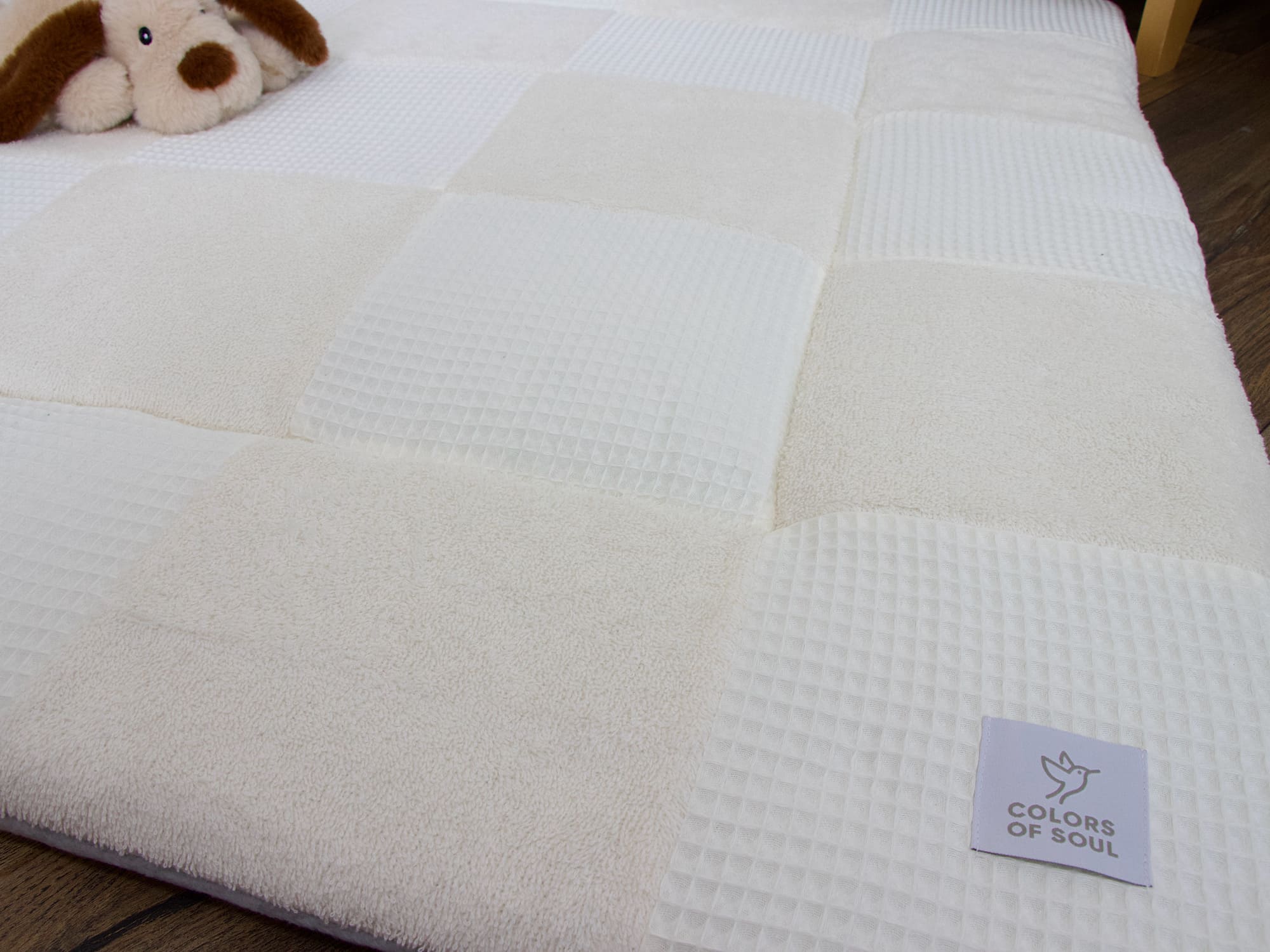 Detailaufnahme der cremefarbenen Patchwork Krabbeldecke mit weicher Struktur