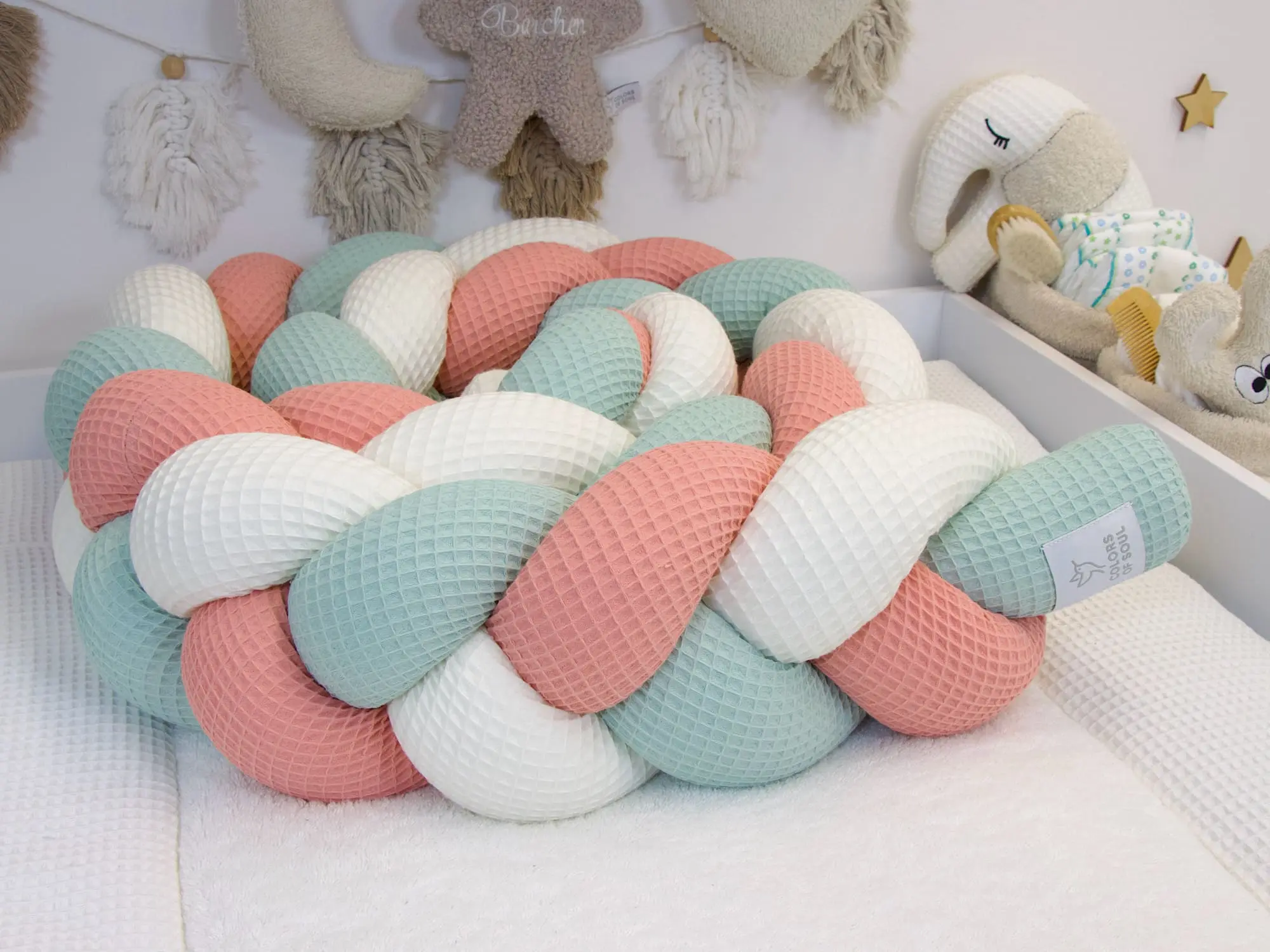 Geflochtene Bettschlange aus Waffelpique in Creme Blush und Hellmint im Babybett