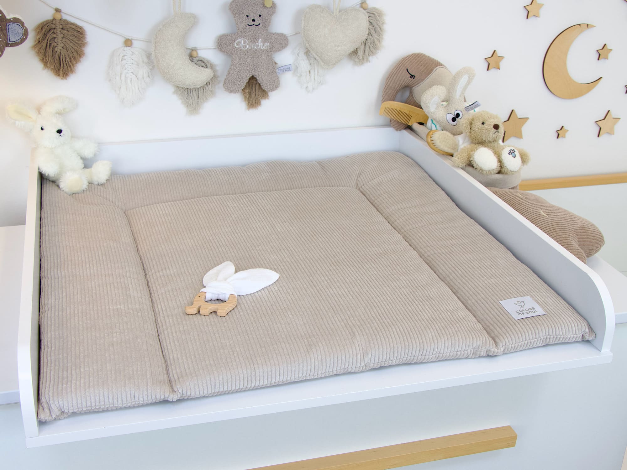 Geschlossene Wickelauflage aus Cord in Hellbeige auf weißem Wickeltisch im natürlichen Babyzimmer