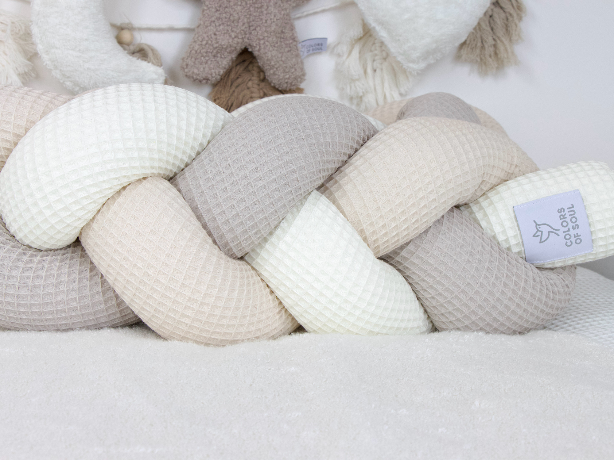 Detailaufnahme der dreifarbigen Bettschlange aus Waffelpique in Creme, Beige und Hellbeige.
