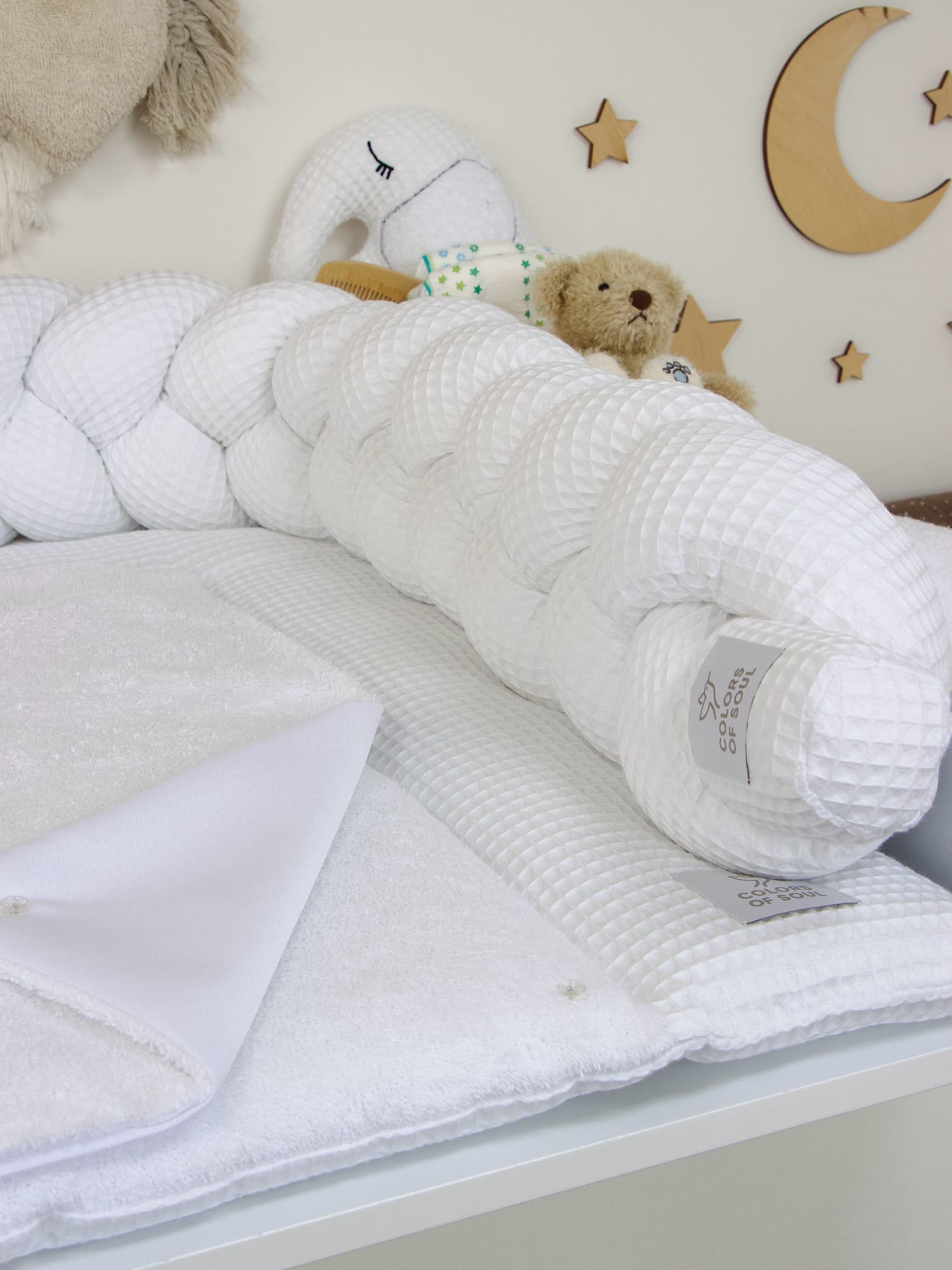 Geflochtene Bettschlange in strahlendem Weiß kombiniert mit Wickelauflage aus Frottee – ideal für neutrale Babyzimmergestaltung.
