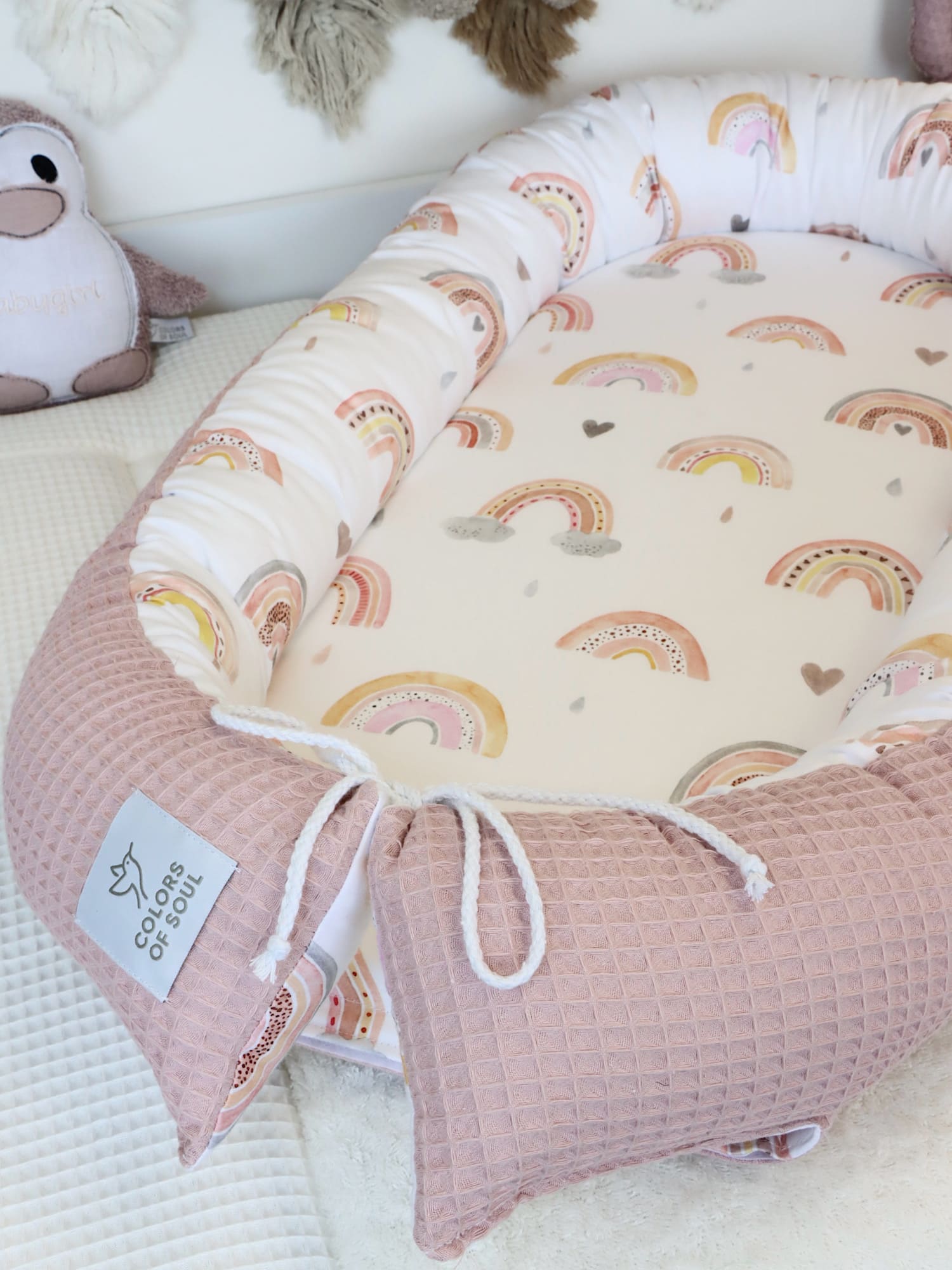 Detailfoto Babynest in Rosé mit Regenbogenprint – weiche Polsterung und handgeknüpfter Kordelverschluss.