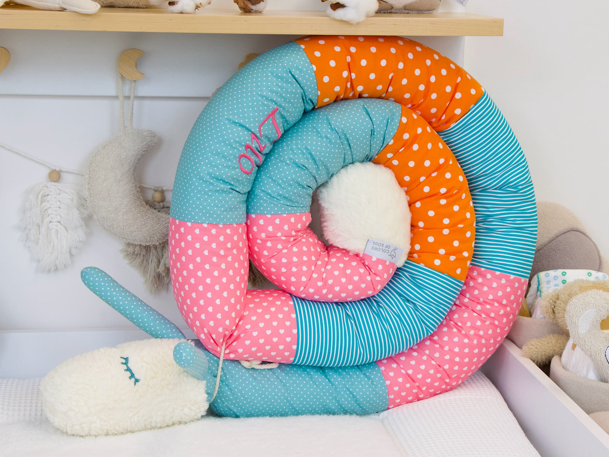 Puckschnecke in Altgrün, Pink, Türkis und Orange im Babybett – personalisierbare Bettschlange handgefertigt