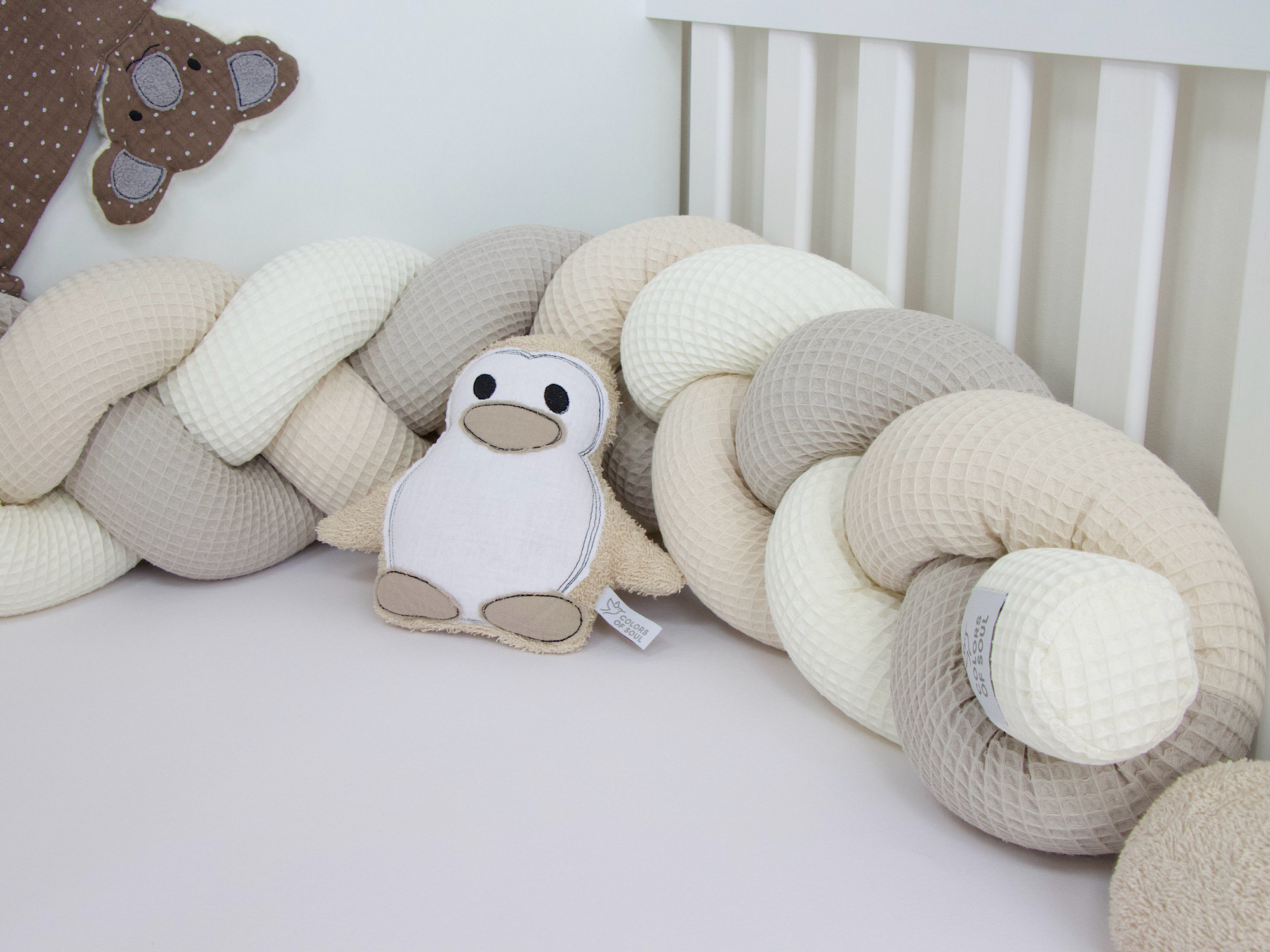 Nahaufnahme der geflochtenen Bettschlange aus Waffelpique in Creme, Beige und Hellbeige im Babybett.