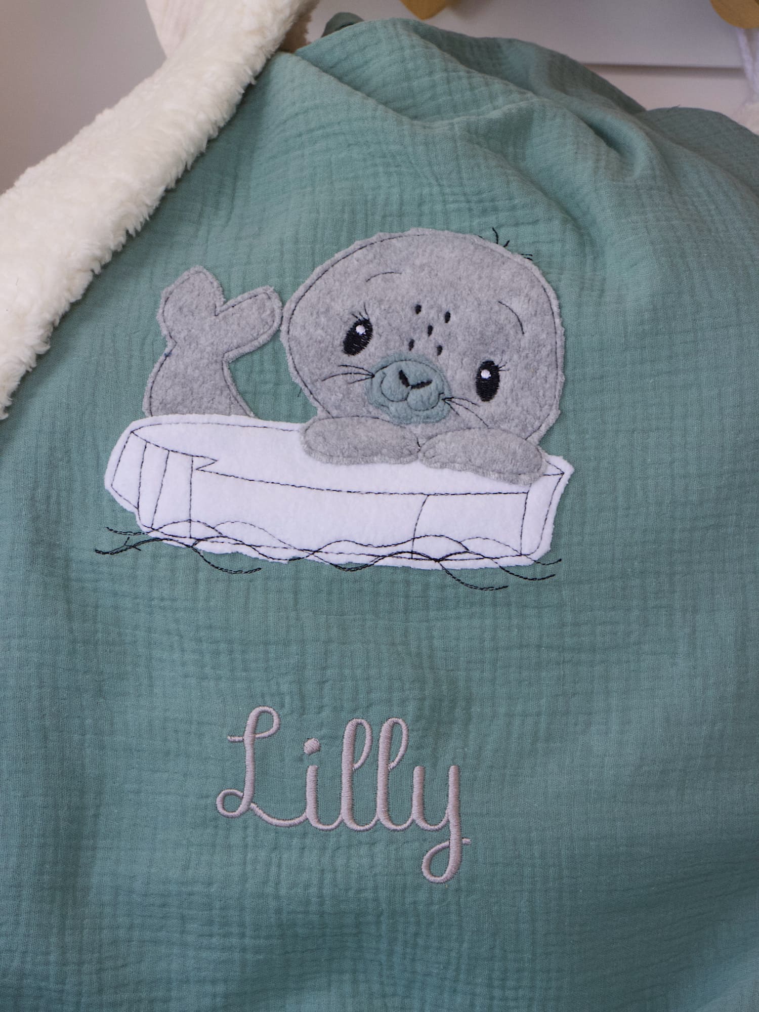 Handgemachte Babydecke Dunkelmint mit Seehund-Motiv und cremefarbener Teddyplüsch-Innenseite – personalisierbar mit Namen und Datum.