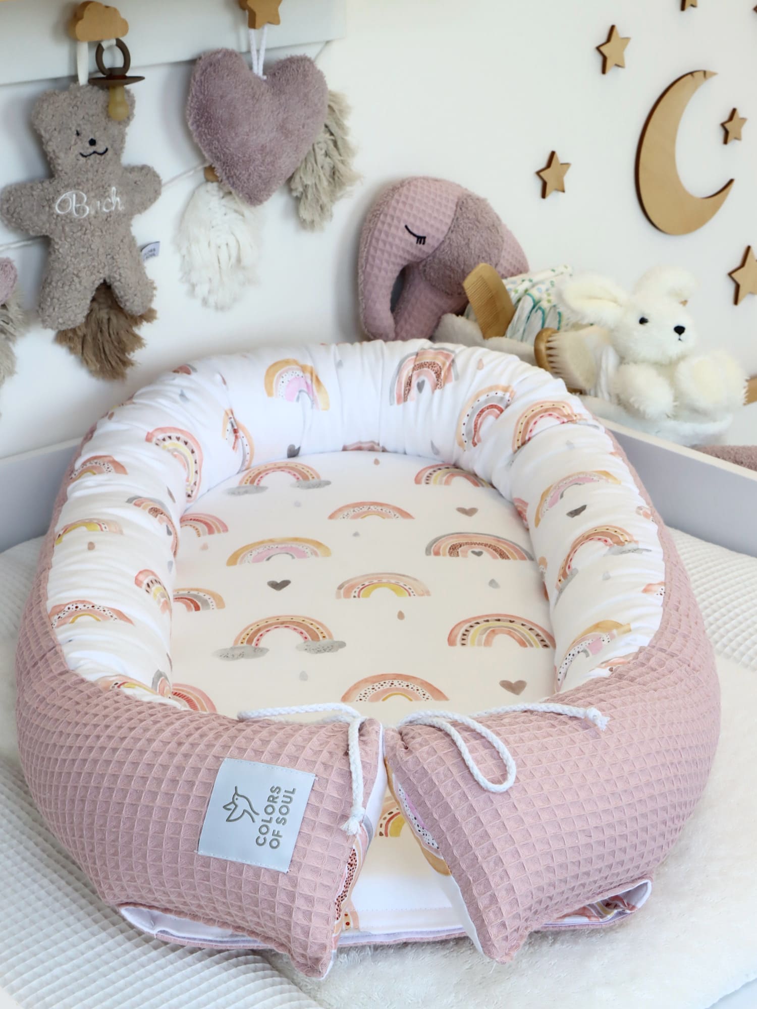 Zweiteiliges Babynest Regenbogen im dekorierten Babyzimmer – Baumwollsatin innen, rosa Waffelpique außen.