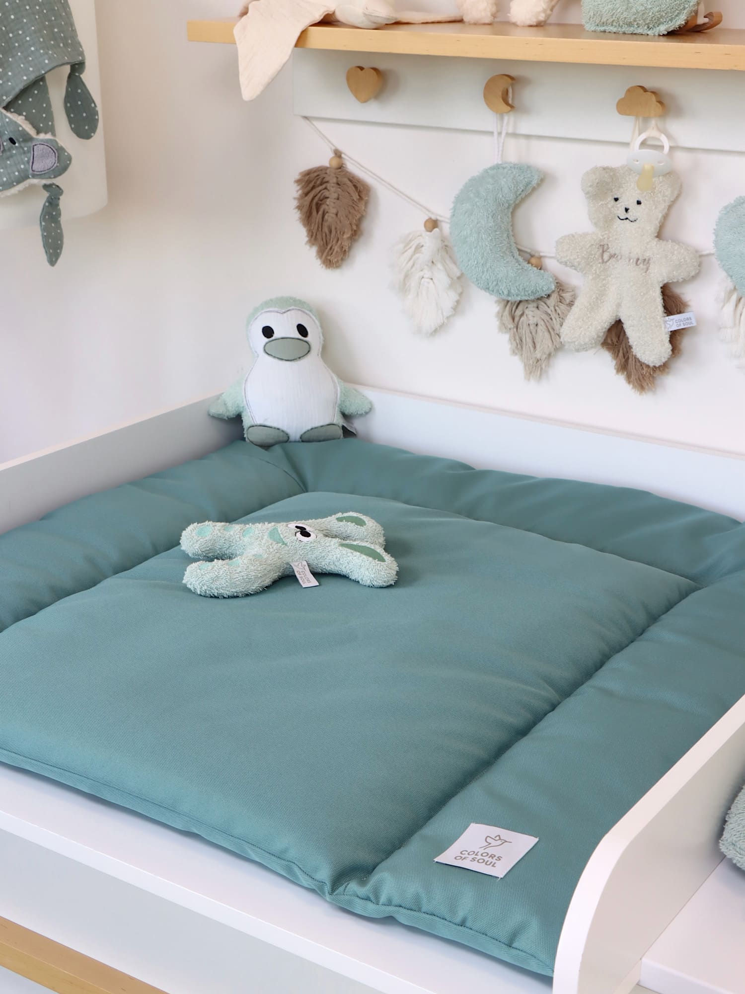 Wickelauflage in Altmint im Babyzimmer, rechts Plüschtier und Pflegeutensilien