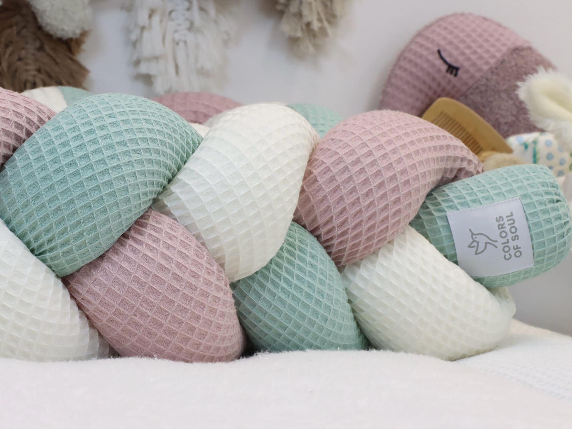 Detailansicht der weichen, geflochtenen Bettschlange in Altrosa, Creme & Hellmint aus Waffelpique als Babybett Bettumrandung