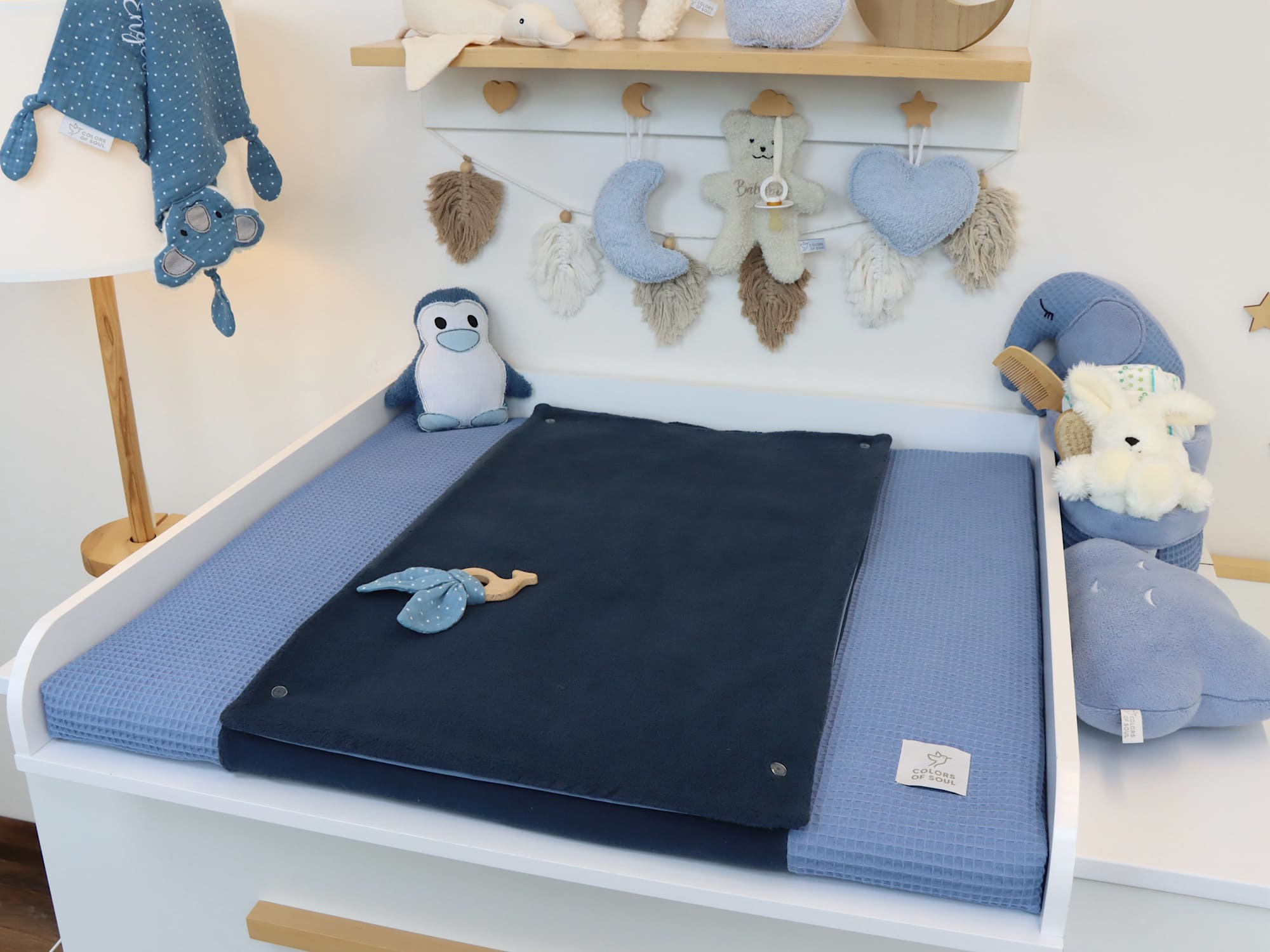 Wickelauflage in zwei Blautönen, kombiniert aus Baumwollfleece und Waffelpique, dekoriert mit Kuscheltieren im Babyzimmer.