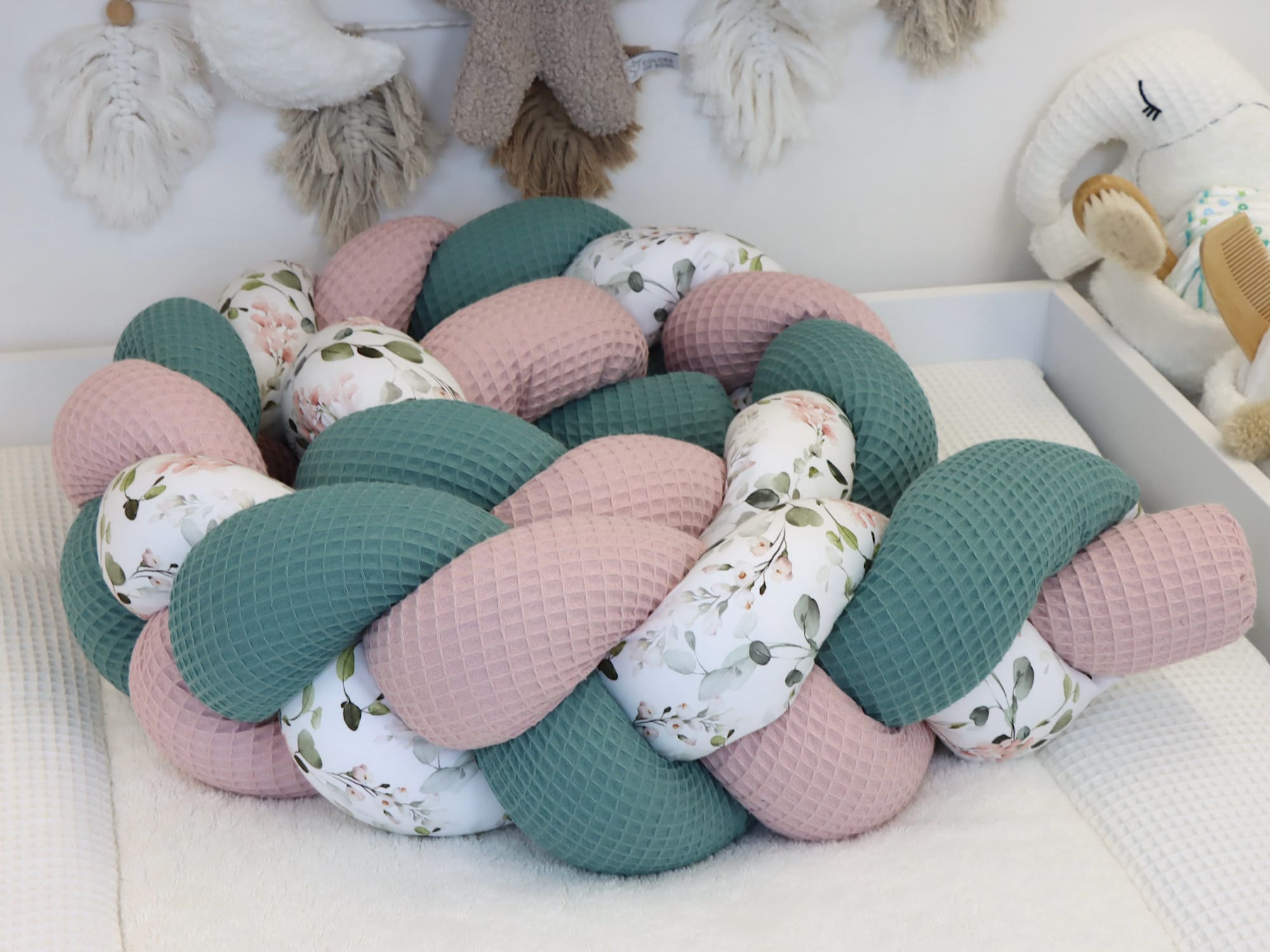 Geflochtene Stoffrolle als weiche Begrenzung im Babybett