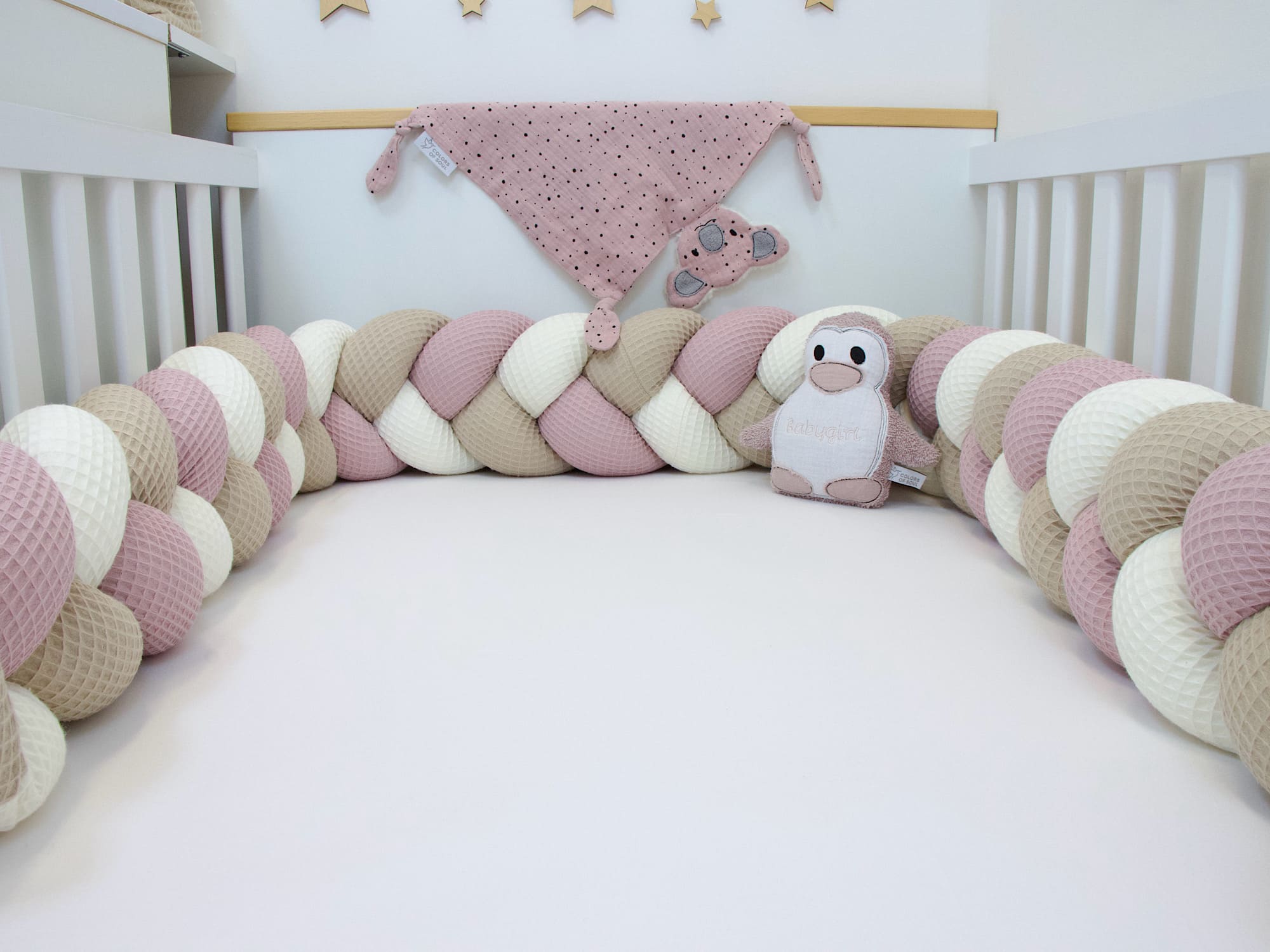 Bettschlange Creme–Altrosa–Beige im Babybett, kombiniert mit passendem rosa Musselintuch und Elefanten-Greifling.