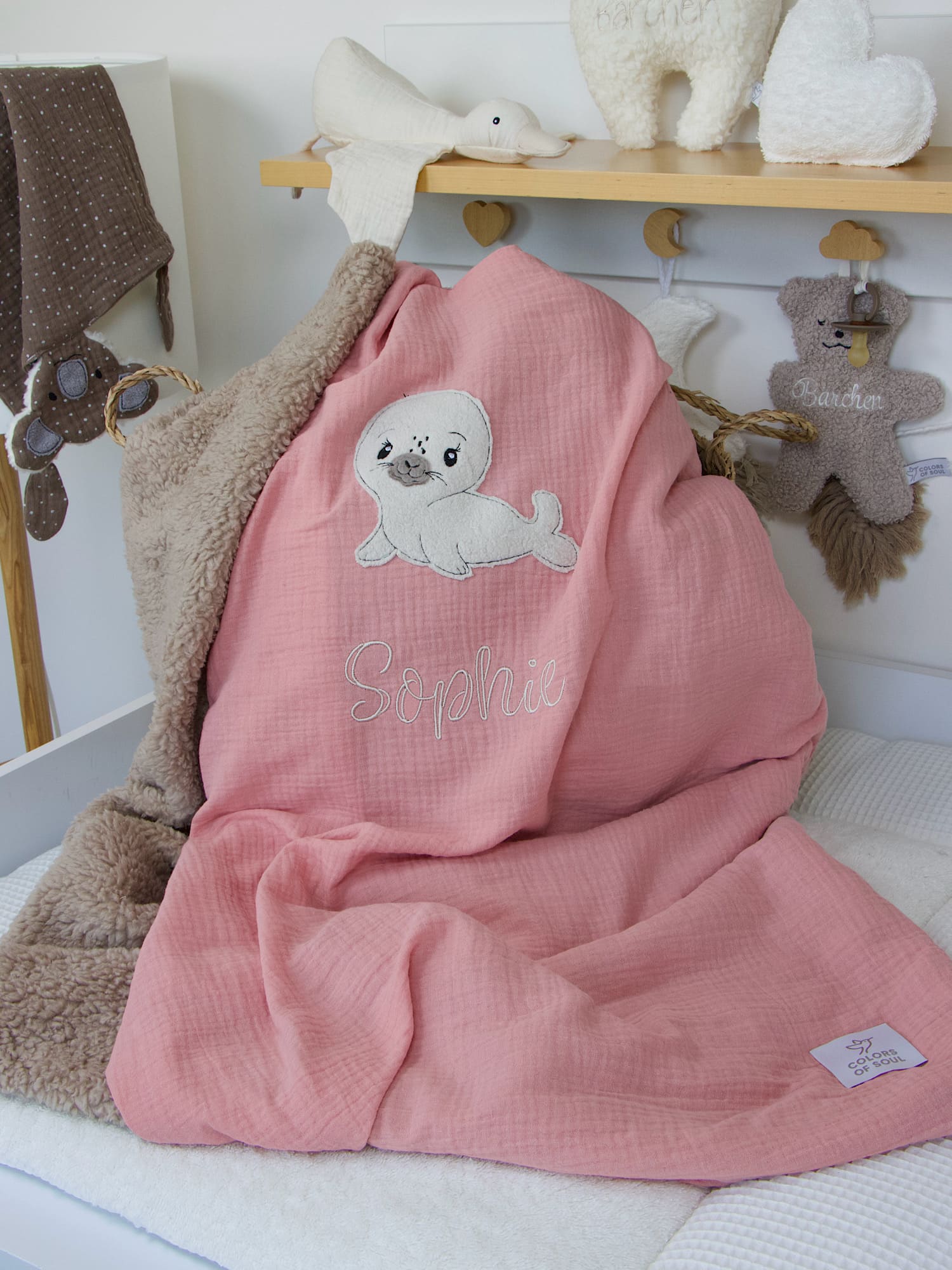 Detailansicht der Seehund-Applikation und Namensstickerei "Sophie" auf der personalisierten Babydecke in Lachsrosa.