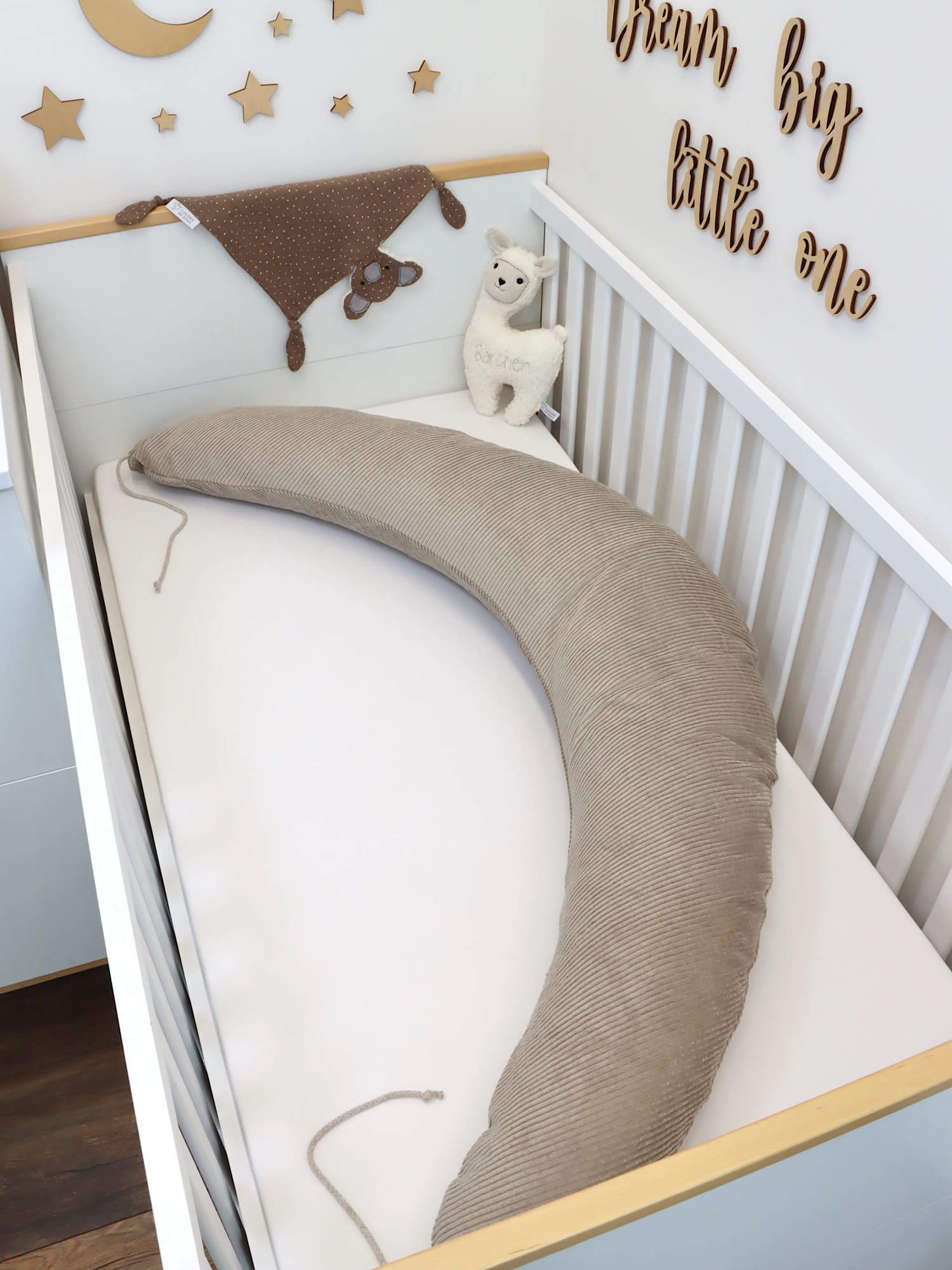 Stillkissen XXL in Beige aus weichem Cord – dekorativ im Babybett aufgestellt, ideal für Stillen und entspanntes Liegen.