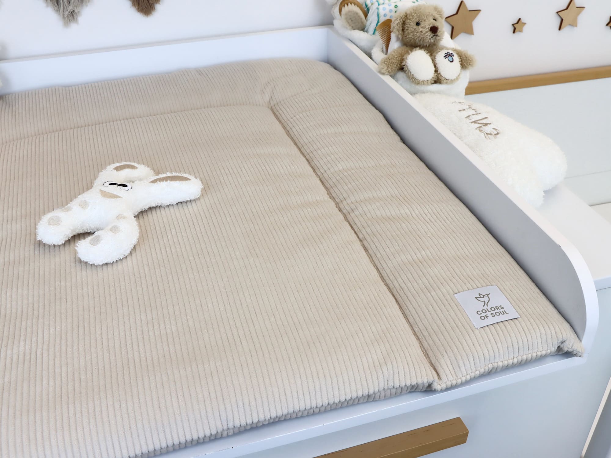 Geschlossene Wickelauflage aus Cord Light Sand auf weißem Wickeltisch im harmonischen Babyzimmer