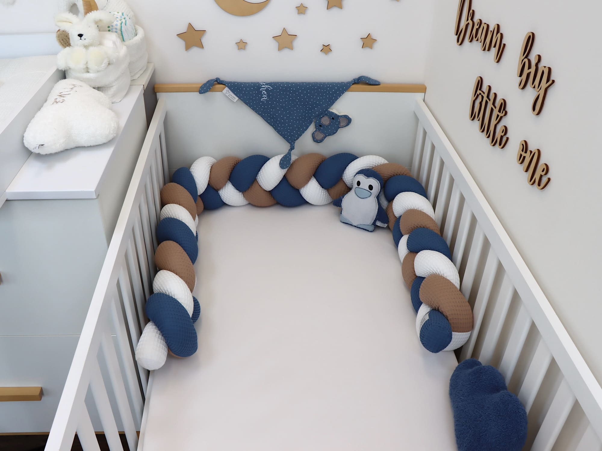 Geflochtene Waffelpique-Bettschlange in Weiß, Dunkelbeige und Jeansblau – weicher Seitenschutz im Babybett, frontal fotografiert.