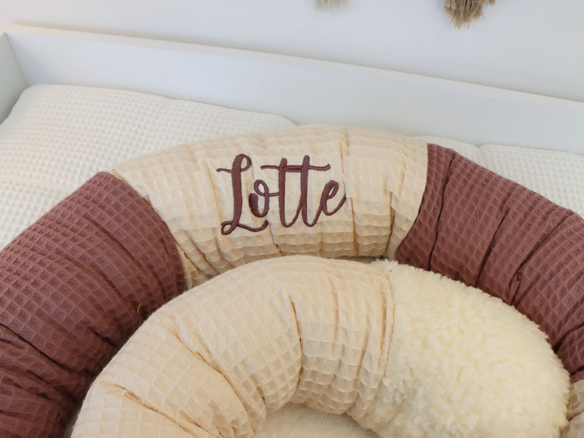 Bettschlange im Babybett ausgelegt – Puckschnecke in hellbeige, natur und alter Malve