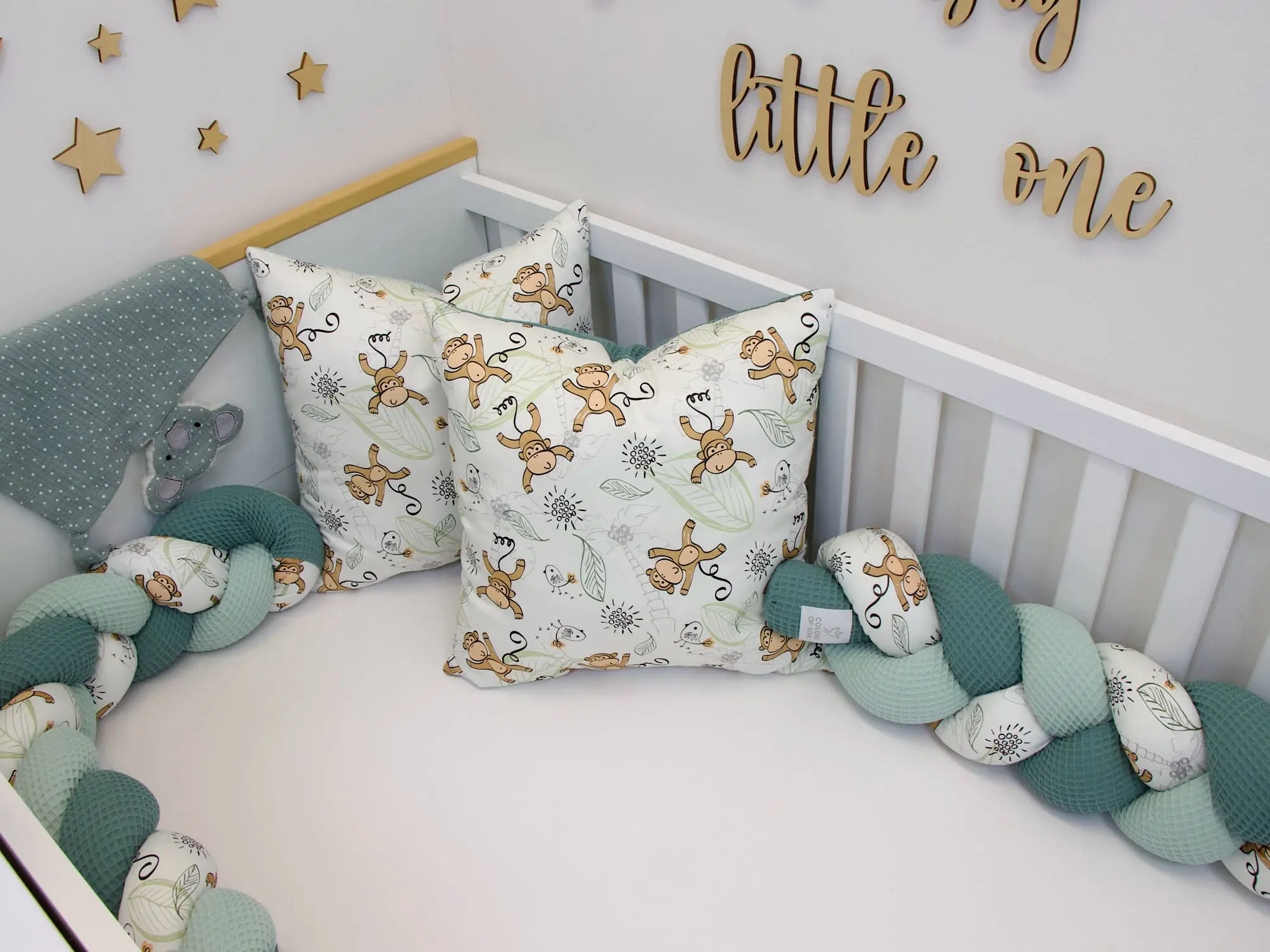 Geflochtene Bettschlange mit Affen-Muster als weiche Bettumrandung im Babybett