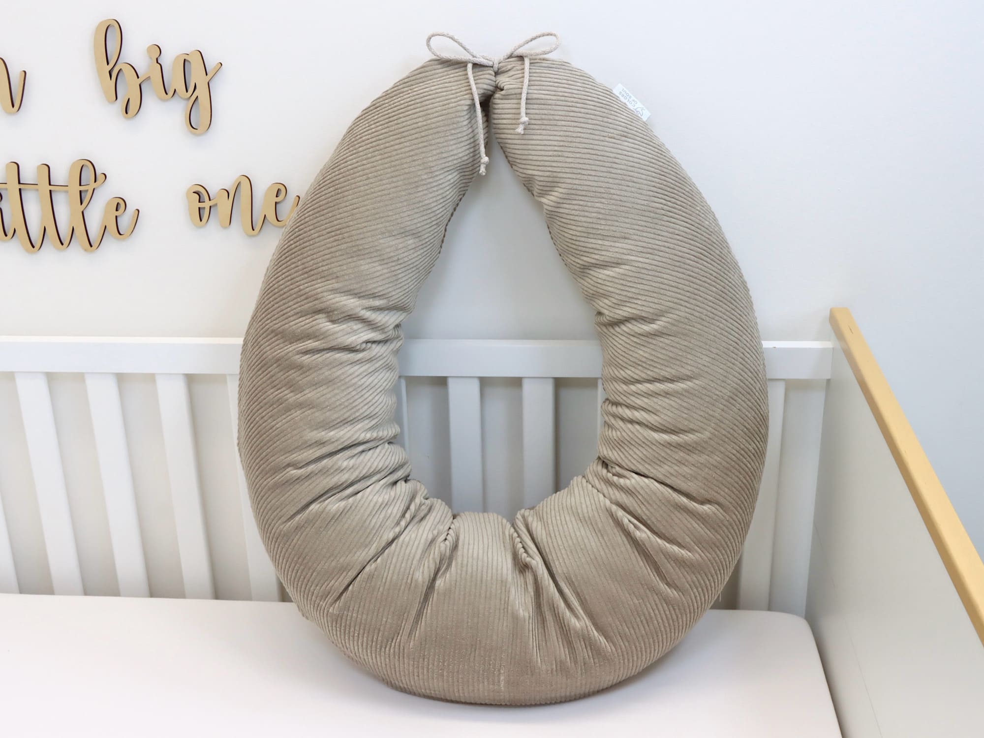 Beiges Stillkissen XXL aus Cord im Babybett – ergonomisches Seitenschläferkissen für Schwangerschaft und Stillzeit.
