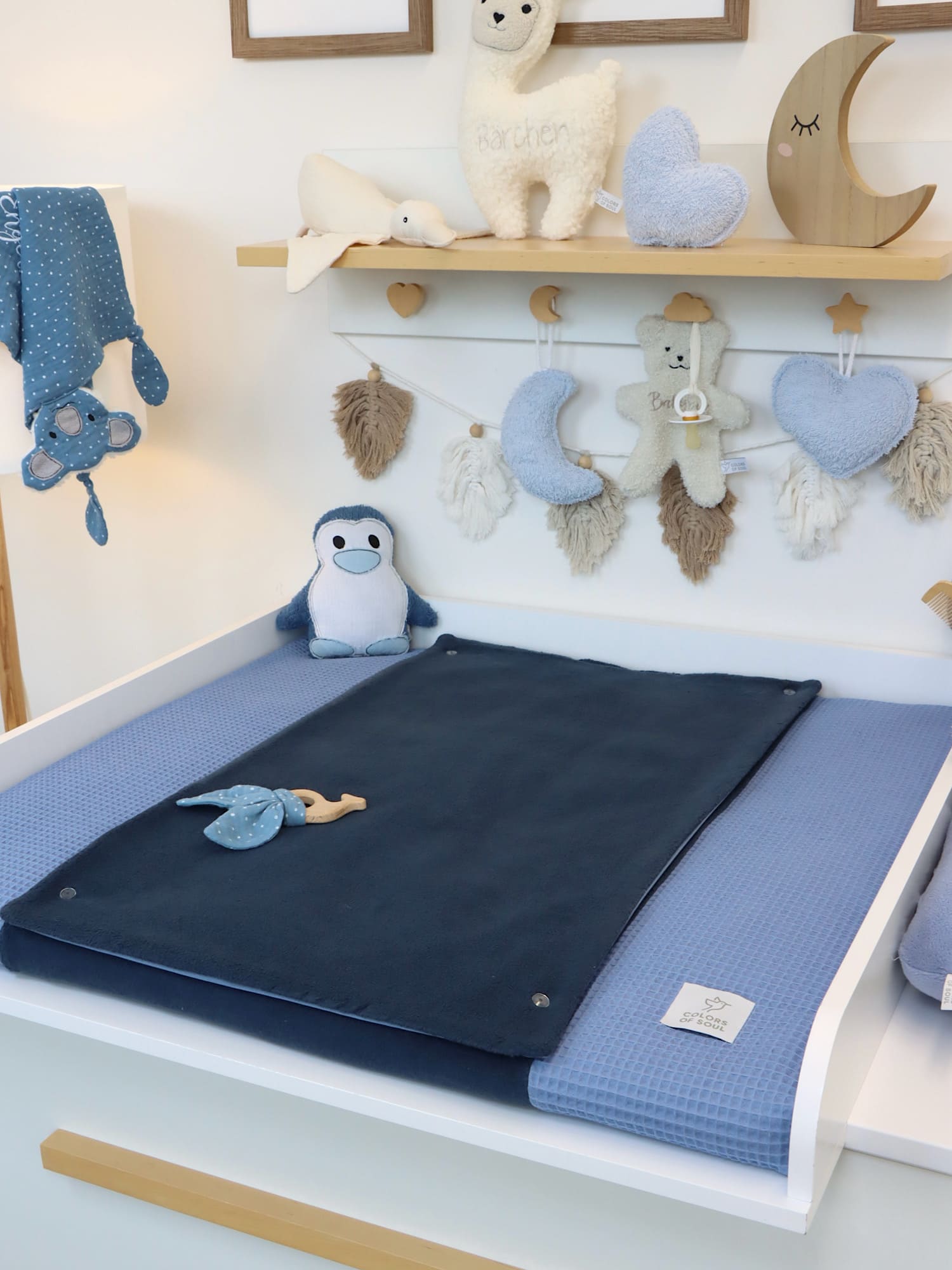Nahaufnahme der Wickelauflage in Blau mit dunkelblauer Fleece-Liegefläche und weichem Waffelpique-Bezug, auf Wickeltisch arrangiert.