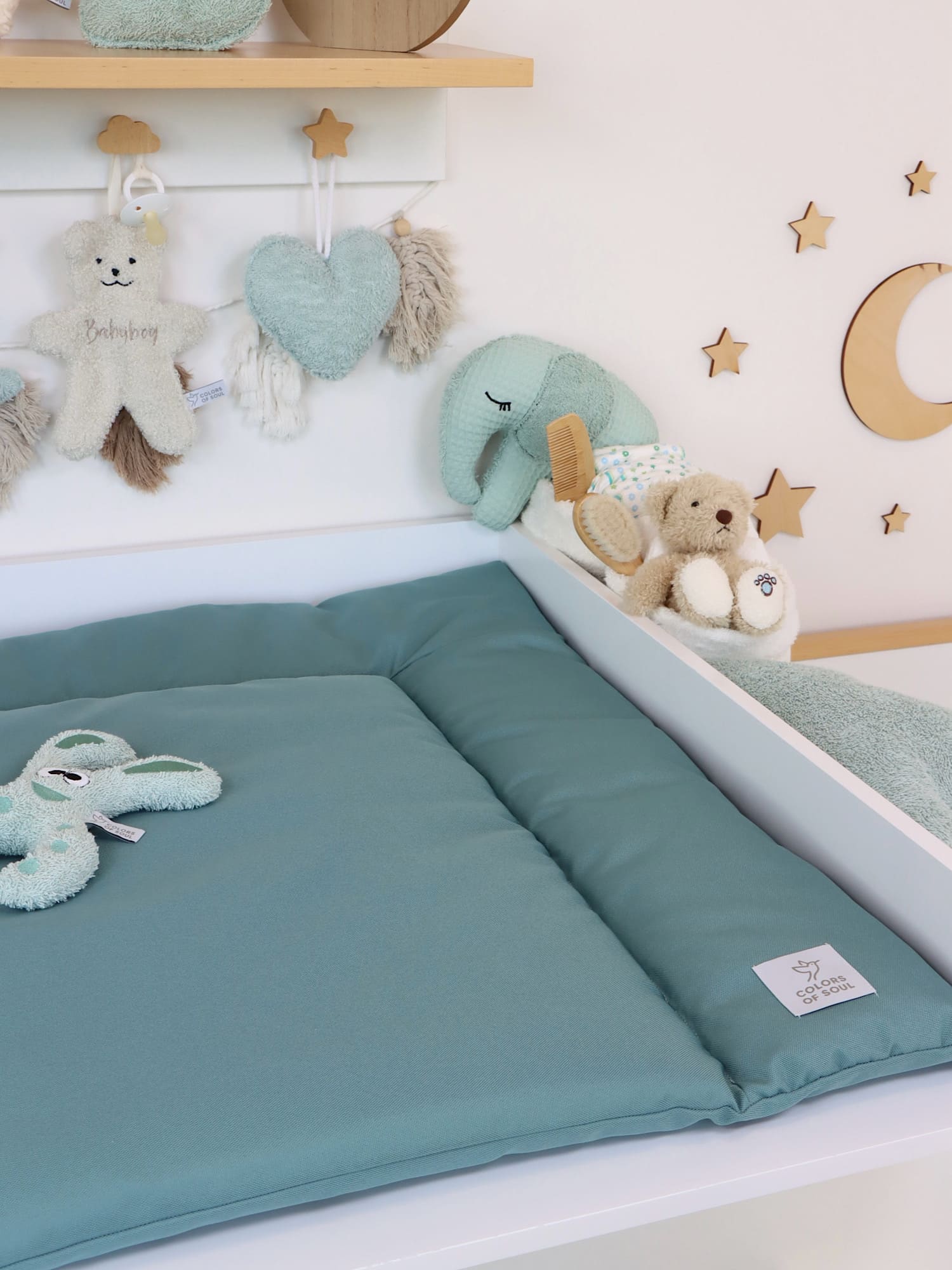 Wickelauflage in Altmint im Babyzimmer, rechts Plüschtier und Pflegeutensilien