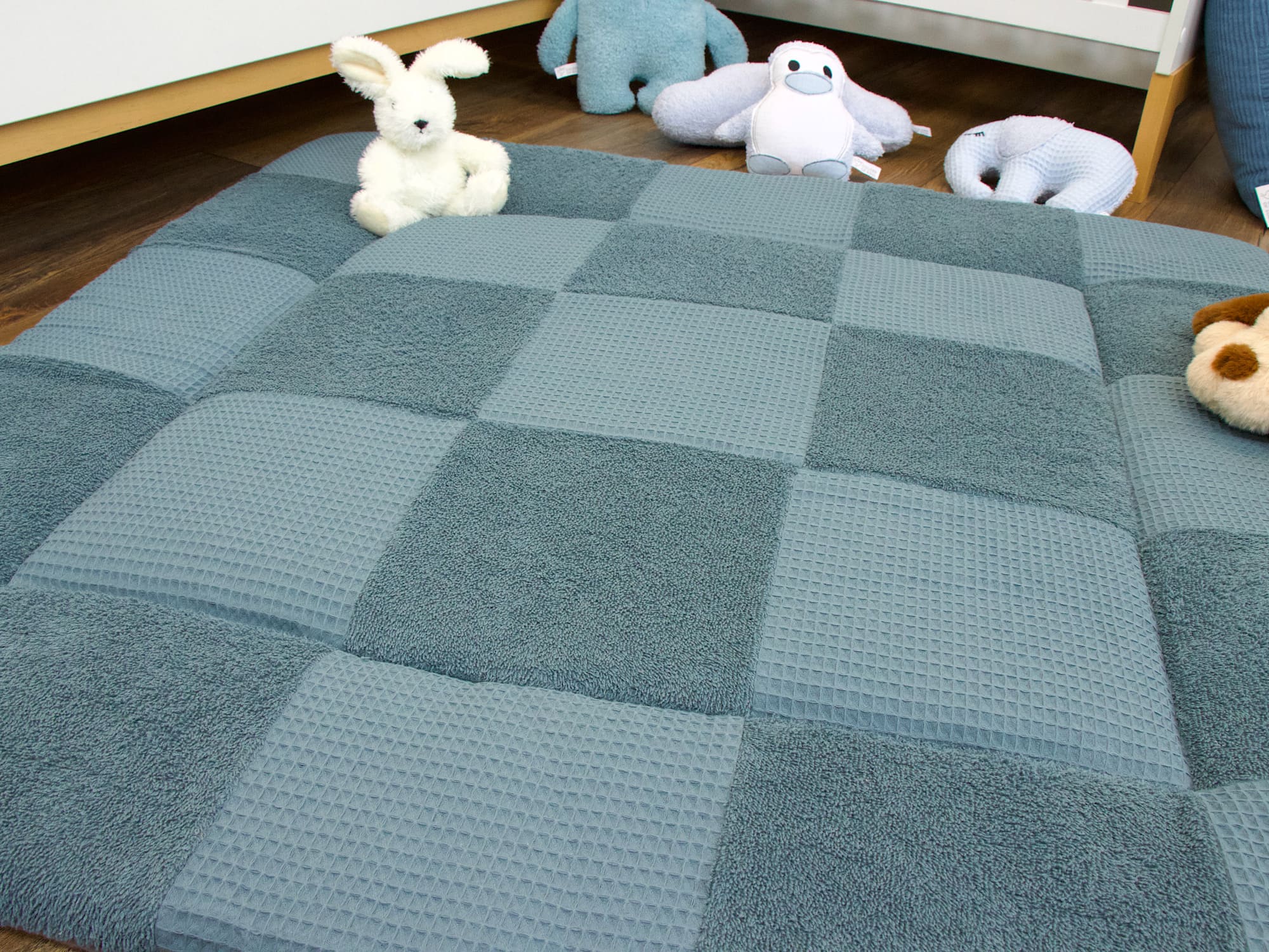 Baby Krabbeldecke in Stahlblau als weiche Spielunterlage vor dem Babybett