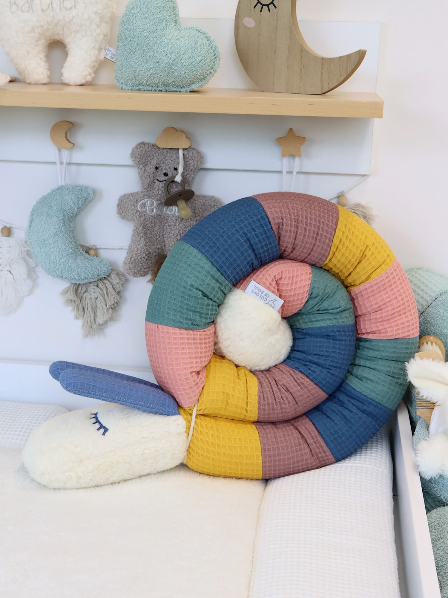 Farbige Bettschnecke Waffelpique in Gelb, Blush, Altgrün, Jeansblau & Alter Malve locker gelegt auf der Wickelauflage.
