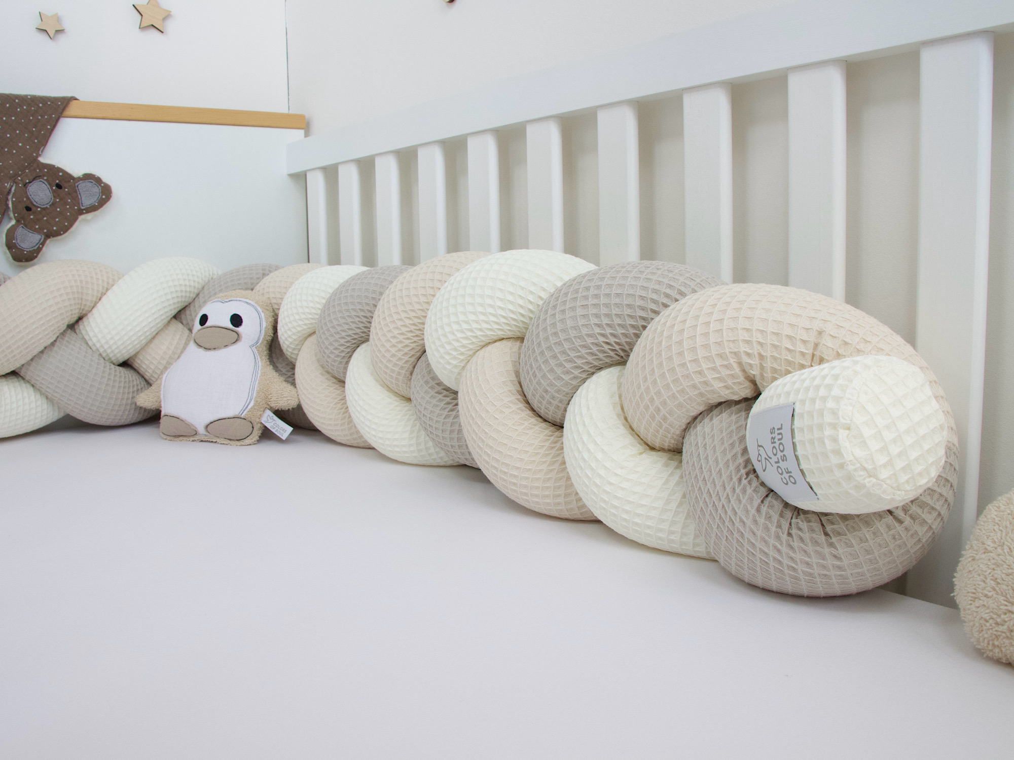Babybett mit geflochtener Bettschlange in Creme, Beige, Hellbeige und Wanddeko Mond und Sterne.