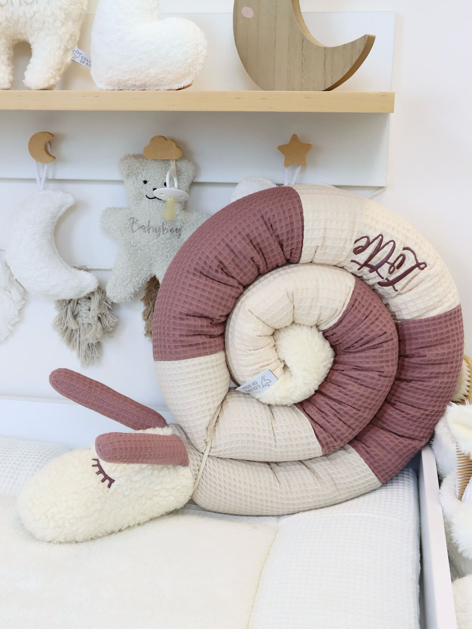 Puckschnecke aus Waffelpique in hellbeige, natur und alter Malve eingerollt im Babybett