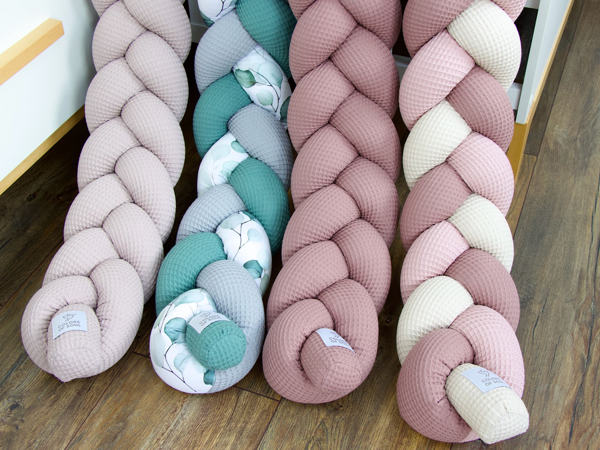 Handgefertigte Bettschlangen in sanften Farben – Altgrün-Grau mit Eukalyptus und Rosé-Beige Varianten nebeneinander