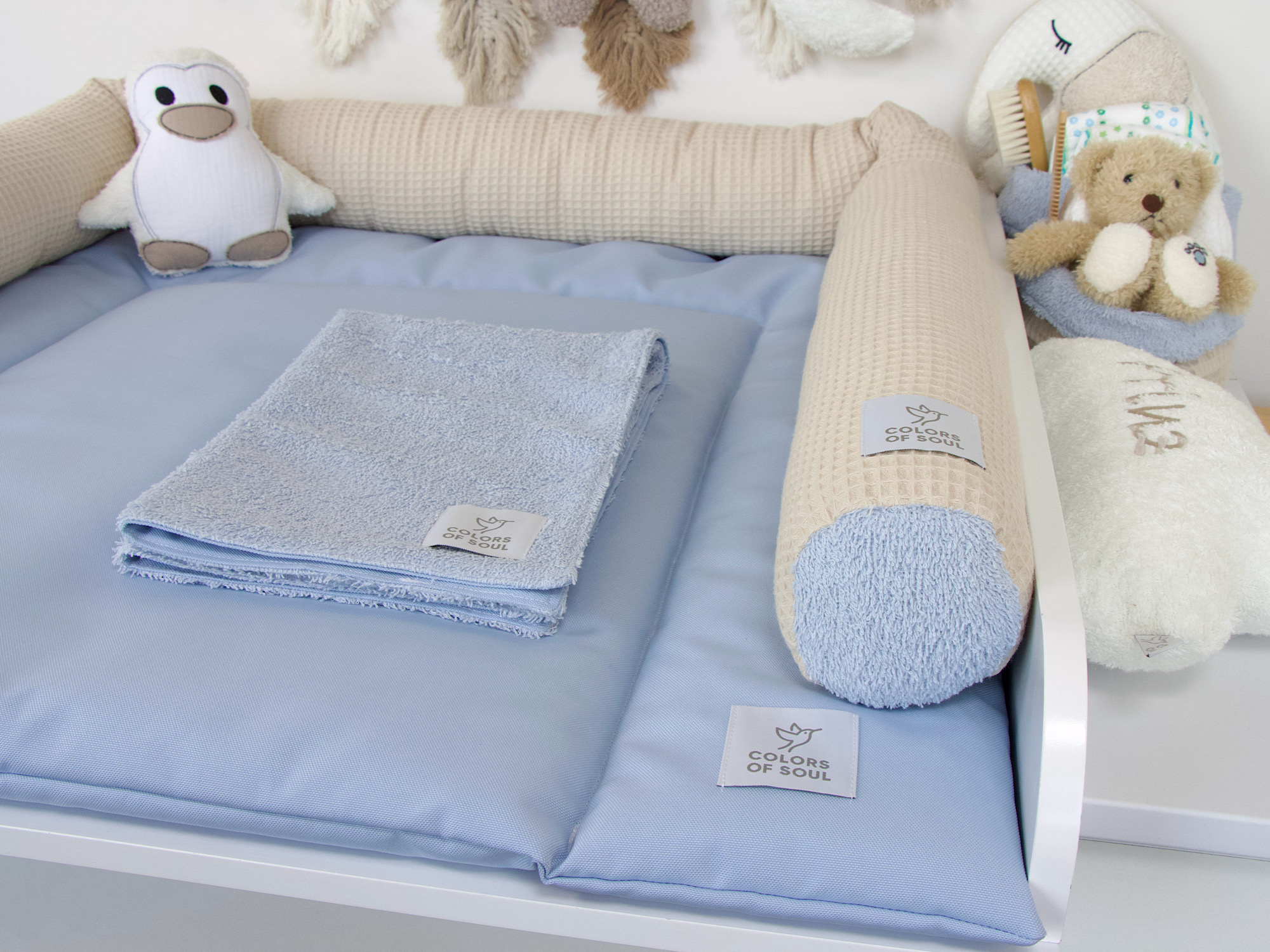 Hellblaue Wickelauflage mit beige-blauer Bettschlange – weiche Polsterung und liebevolle Details mit Stofftieren und Bürstenkorb