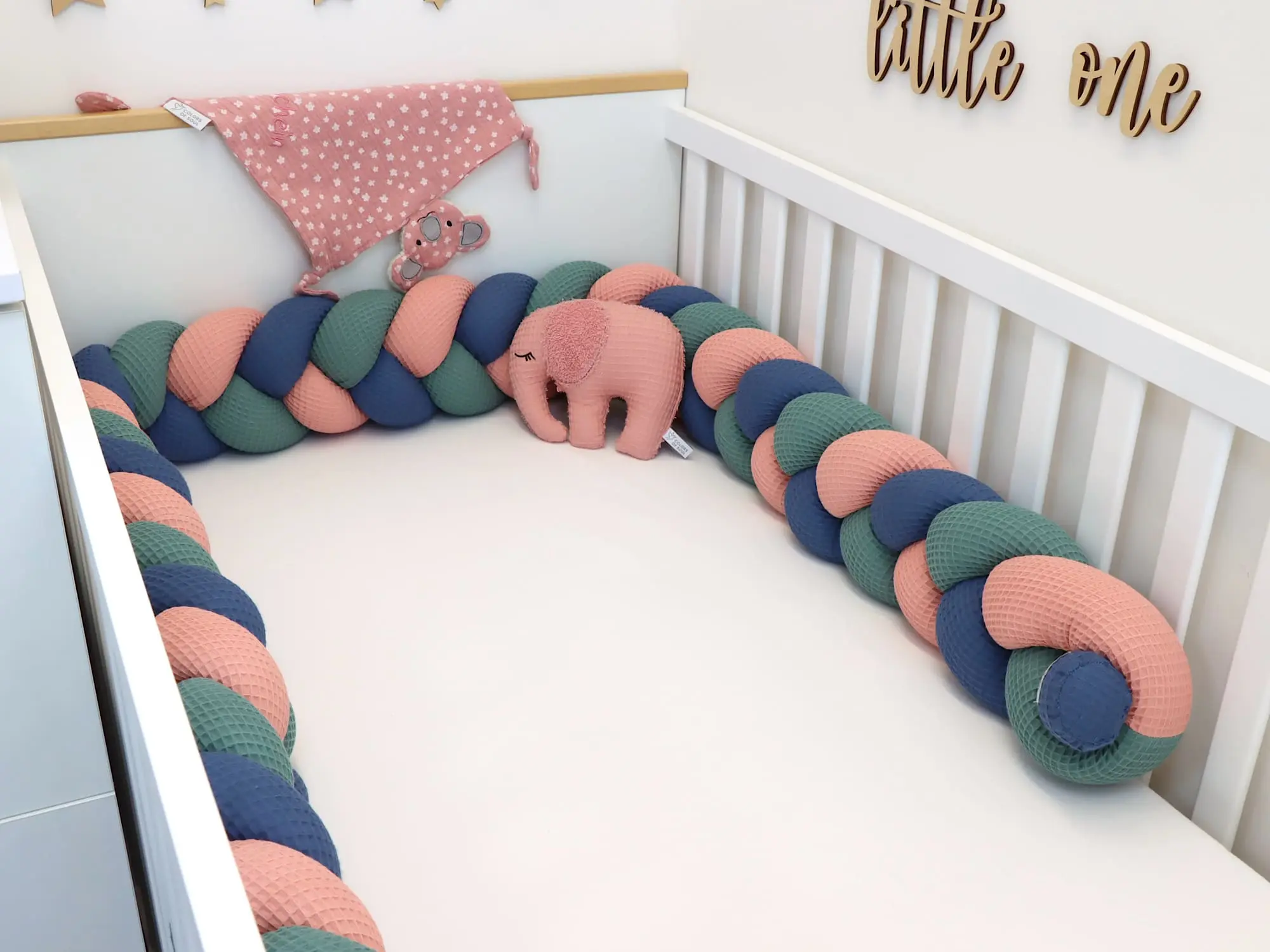 Geflochtene Nestchenschlange in Blush Altgrün Jeansblau im weißen Babybett
