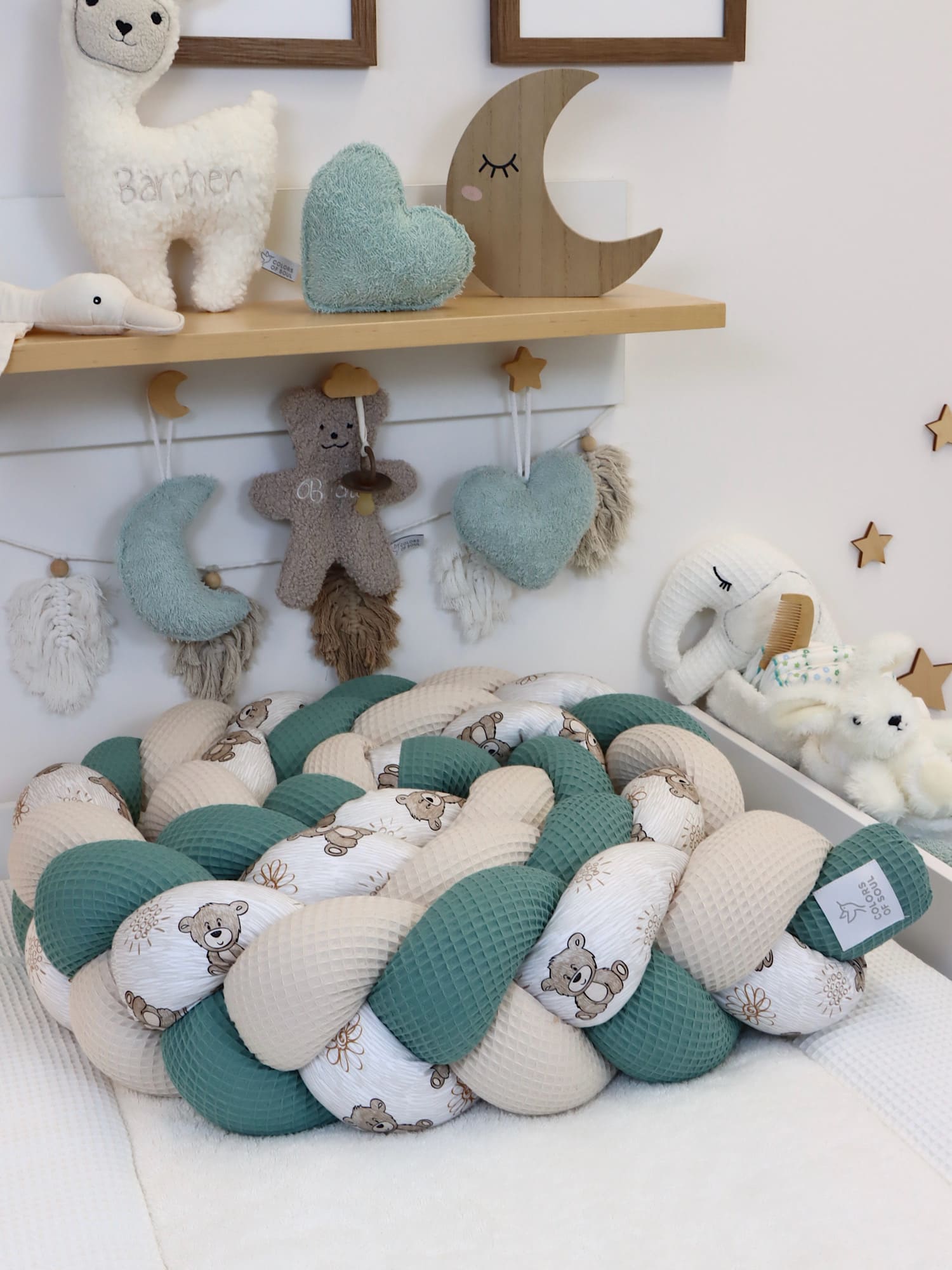 Geflochtene Bettschlange Altgrün & Natur mit süßen Bärchen, dekorativ im Babyzimmer platziert.