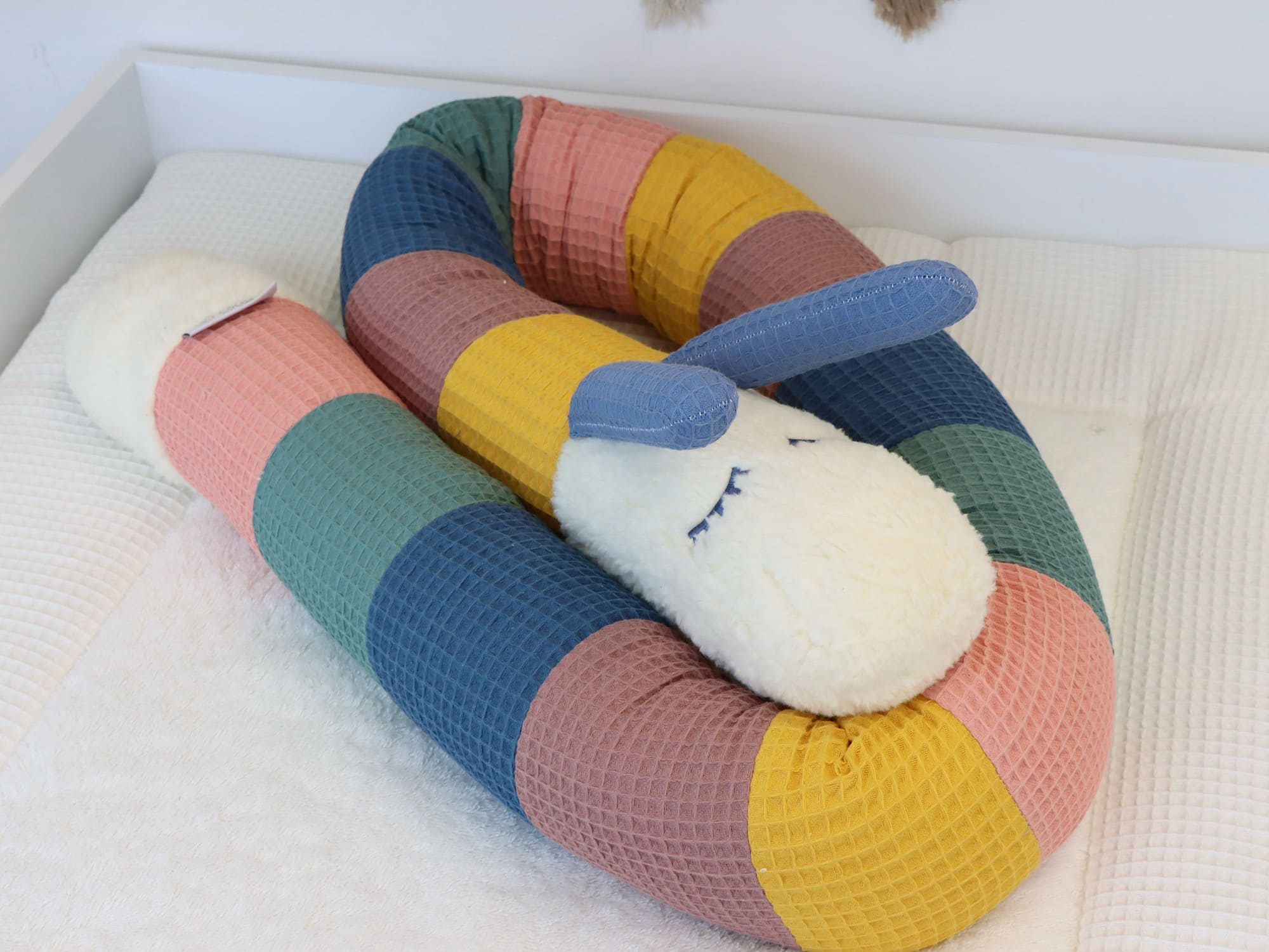 Puckschnecke aus Waffelpique in Gelb, Blush, Altgrün, Jeansblau und Alter Malve zusammengerollt auf der Wickelauflage.