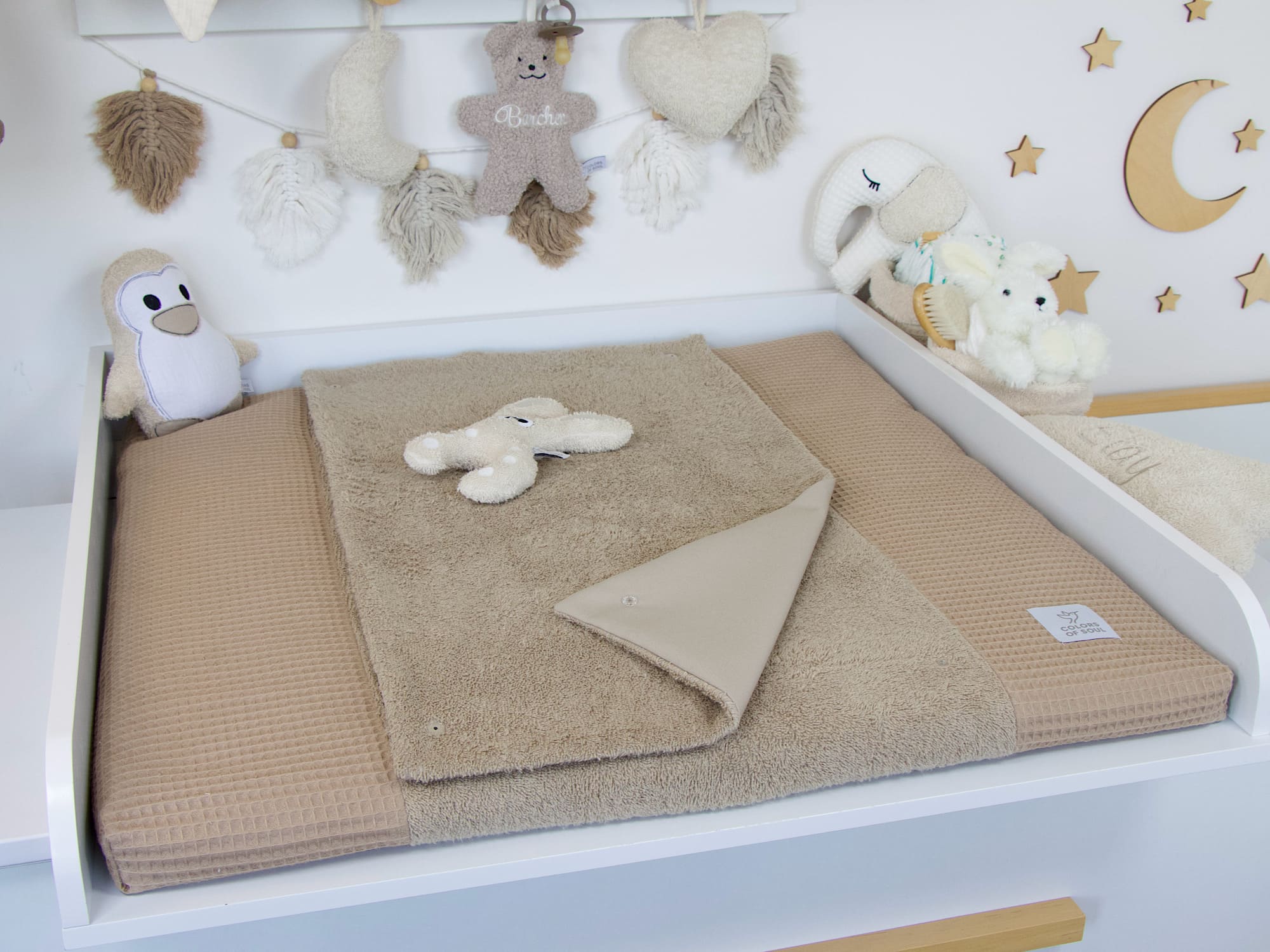 Wickelauflage mit Bezug aus Frottee und Waffelpique in Dunkelbeige auf modernem Wickeltisch – harmonisches Babyzimmer mit Sternen und Kuscheltieren.