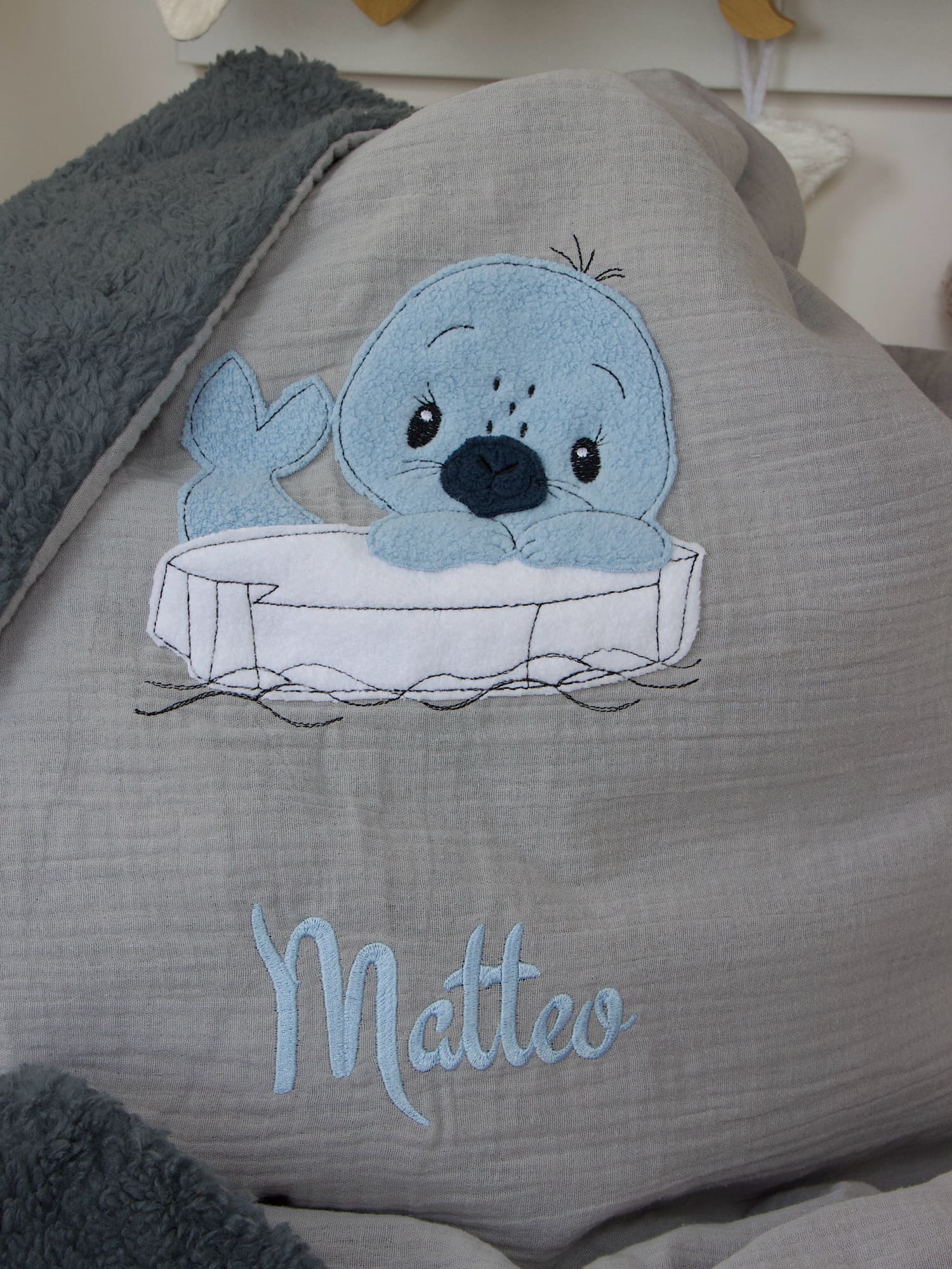 Baby Kuscheldecke hellgrau mit Seehund-Motiv und Namensstickerei, dekoriert im Kinderzimmer