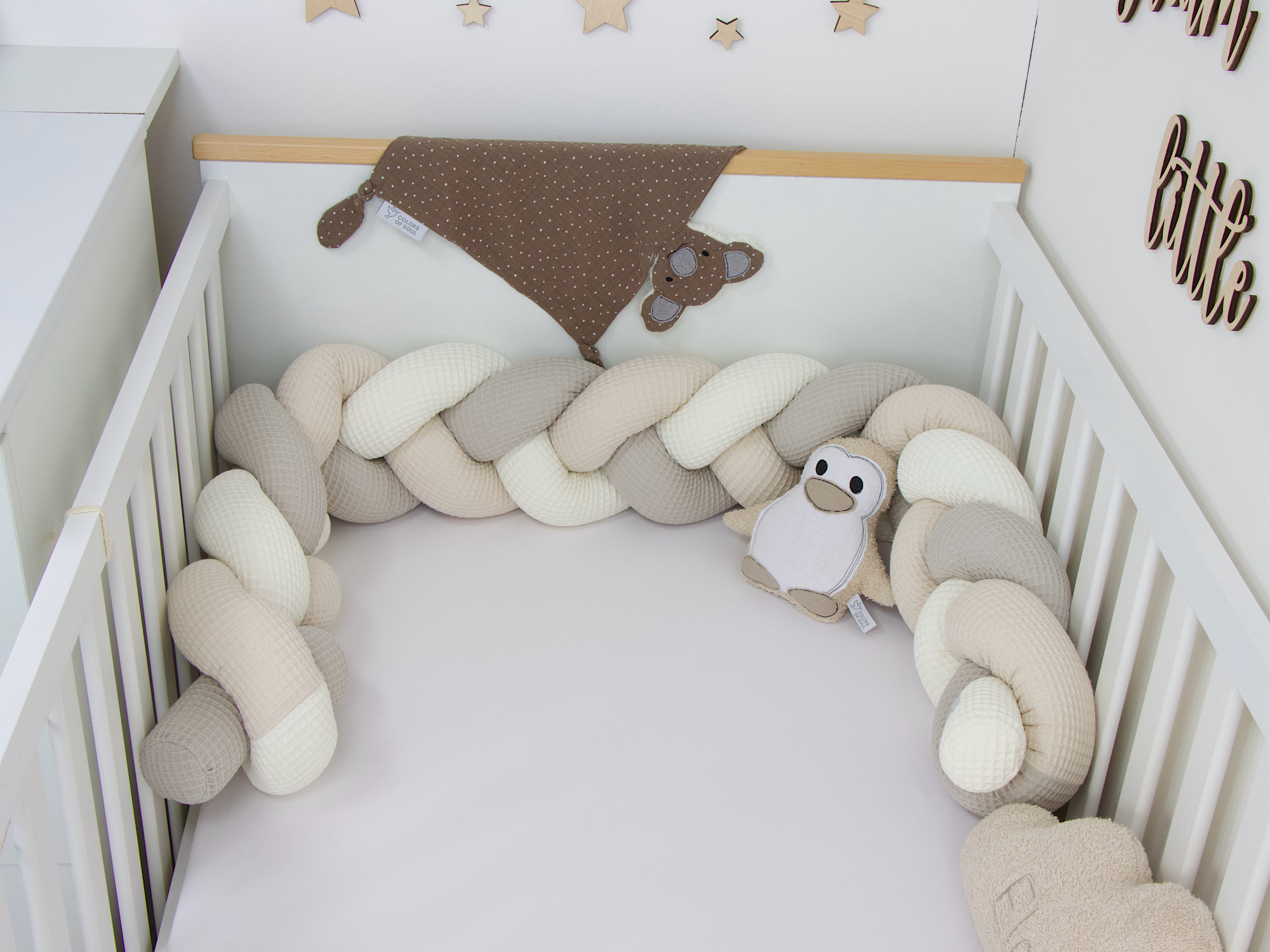 Bettschlange in Creme Beige Hellbeige als Kantenschutz im weißen Babybett mit beruhigender Wanddeko.