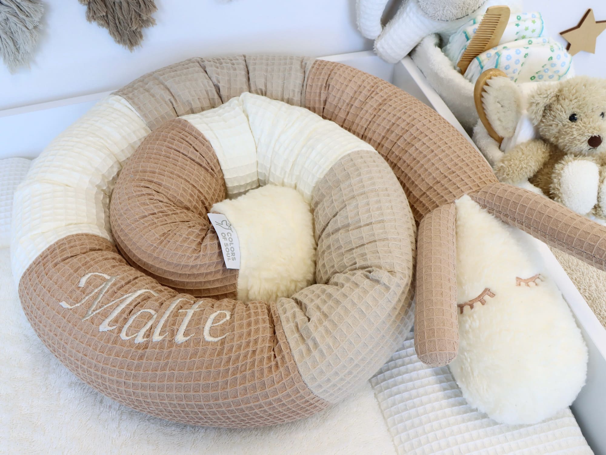 Kuschelige Puckschnecke aus Waffelpique in Camel, Beige und Creme – dekorativ im Babybett arrangiert, handgefertigt mit Stickerei.