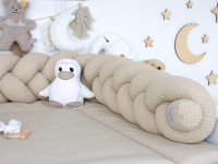Geflochtene Bettschlange aus Waffelpique Beige auf einer Wickelauflage, dekoriert mit Stoffanhängern im Babyzimmer.
