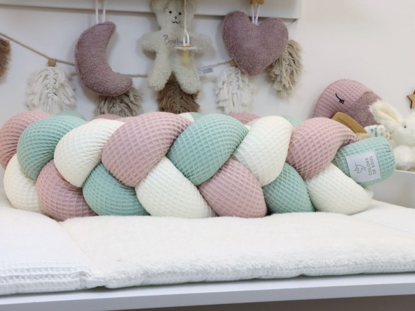 Geflochtene Bettschlange aus Waffelpique Altrosa, Creme und Hellmint auf der Wickelkommode als dekorative Bettumrandung