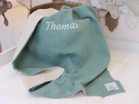 Personalisierte Babydecke aus Musselin Mint und Waffelpique Hellbeige mit eingesticktem Namen „Thomas“, dekorativ auf Babybett präsentiert.