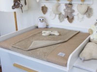 Handgemachte Wickelauflage mit Bezug und Inlett aus Waffelpique und Frottee in Dunkelbeige auf weißem Wickeltisch – stilvolles Babyzimmer mit Kuscheltieren.
