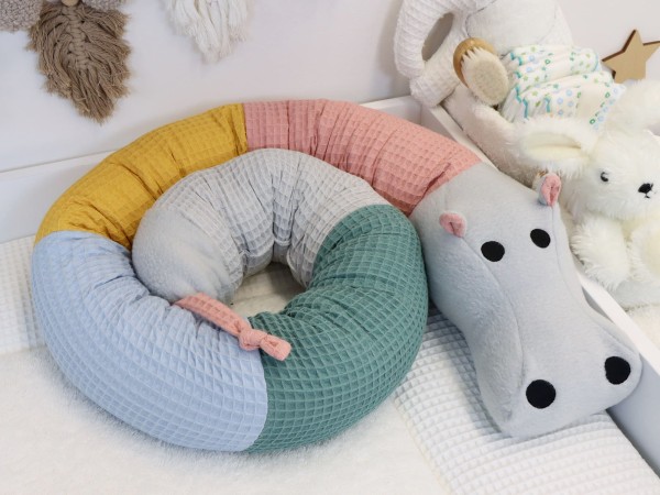 Handgemachte Bettschlange Nilpferd aus Waffelpique in blush, gelb, hellblau, altgrün und hellgrau im Babybett – liebevoll genähtes Babygeschenk