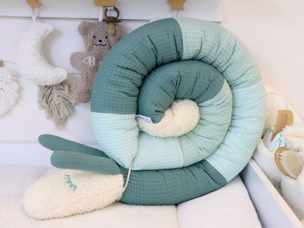 Puckschnecke aus Waffelpique in Altgrün, Pastellmint und Hellmint, eingerollt im Babybett mit weichem Teddyplüsch-Kopf.
