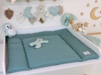 Abwaschbare Wickelauflage in Altmint auf weißer Wickelkommode, liebevoll dekoriertes Babyzimmer im Hintergrund