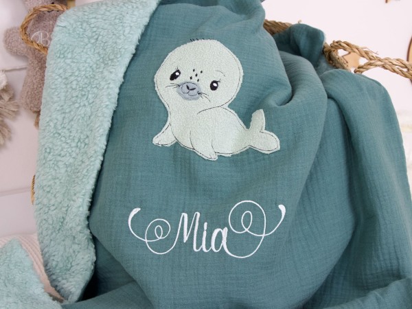 Detailaufnahme der Seehund-Applikation und Namensstickerei "Mia" auf der personalisierten Babydecke Dunkelmint